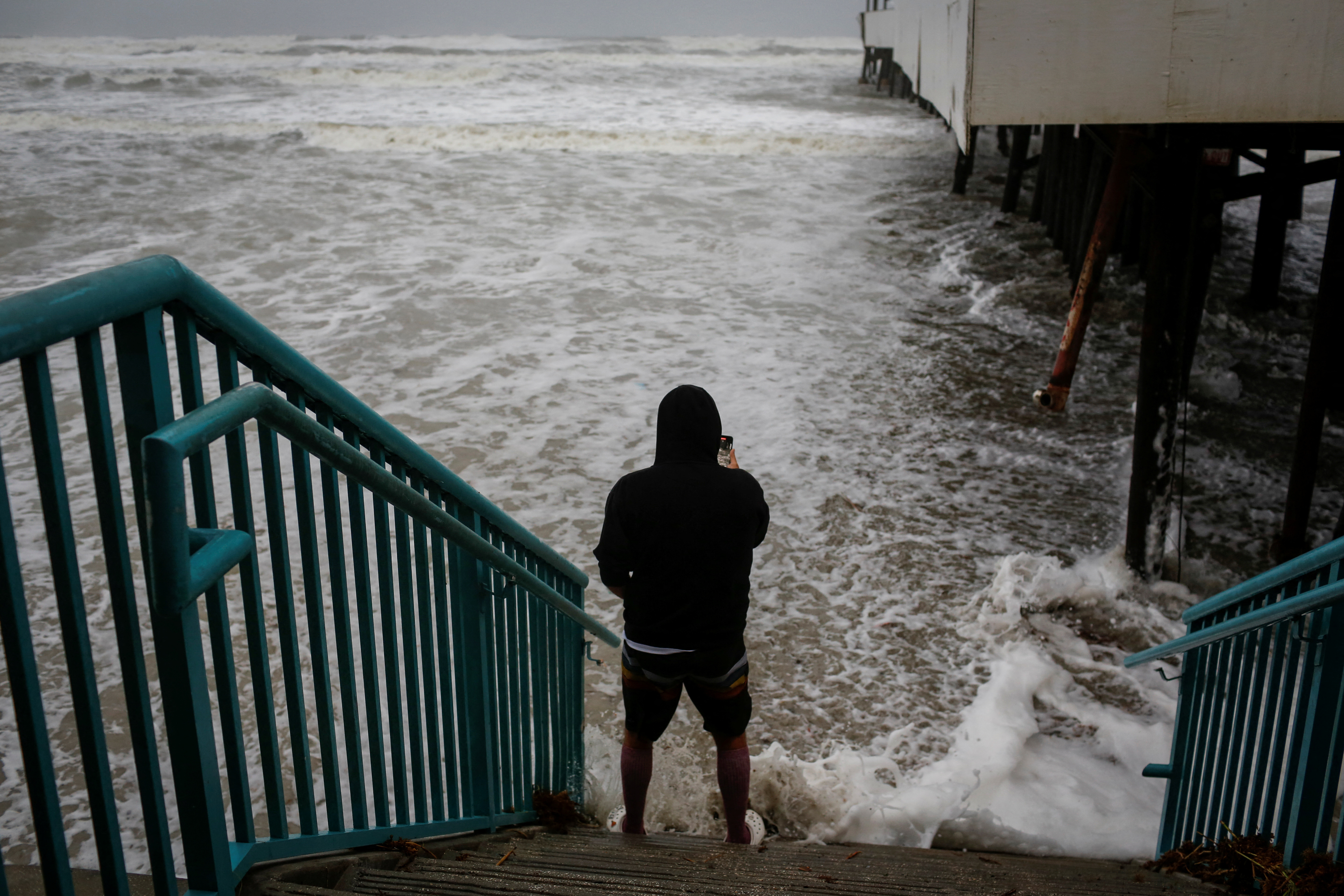 A man uses his phone to take photos ahead of the expected arrival of Hurricane Nicole, in Daytona Beach, Florida, U.S., November 9, 2022. REUTERS/Marco Bello