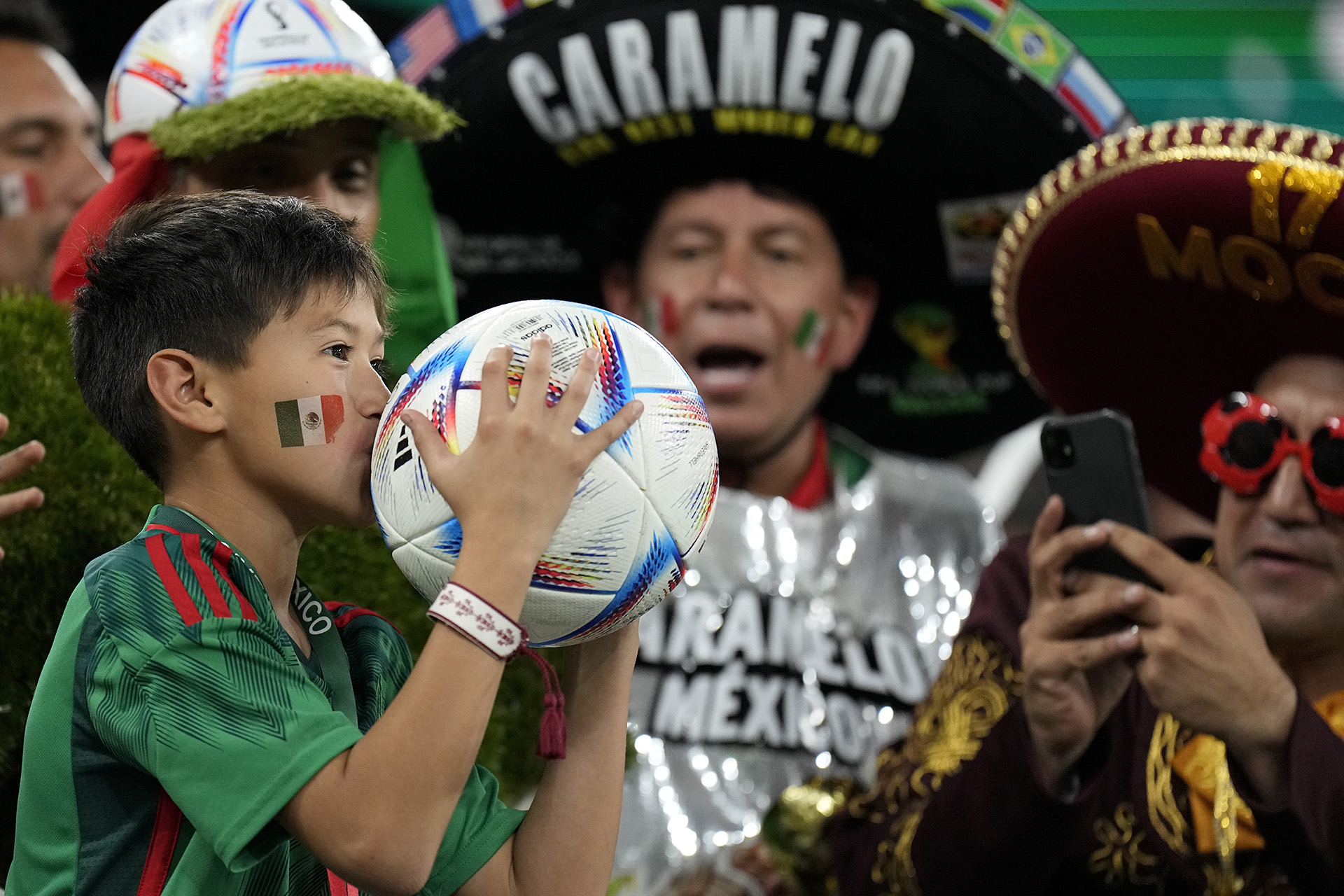 A fan of Mexico kisses a ball during a World Cup group C soccer match against Poland at the Stadium 974 in Doha, Qatar, Tuesday, Nov. 22, 2022. (AP Photo/Martin Meissner)