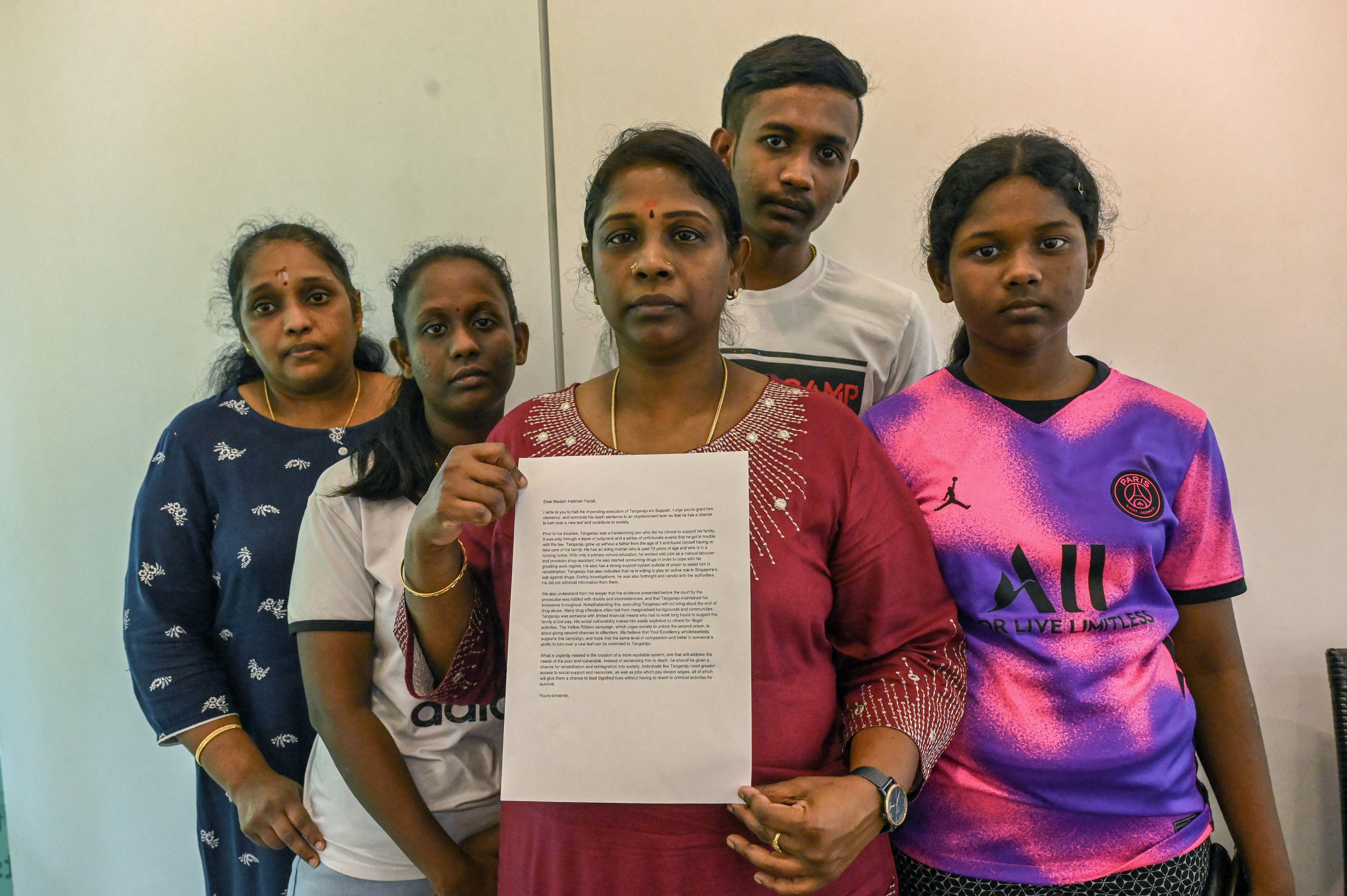 Leelavathy Suppiah, hermana del narcotraficante condenado Tangaraju Suppiah, posa con miembros de su familia mientras sostiene una carta de petición de clemencia en Singapur el 23 de abril de 2023. (Foto de Roslan RAHMAN/AFP/Archivo)