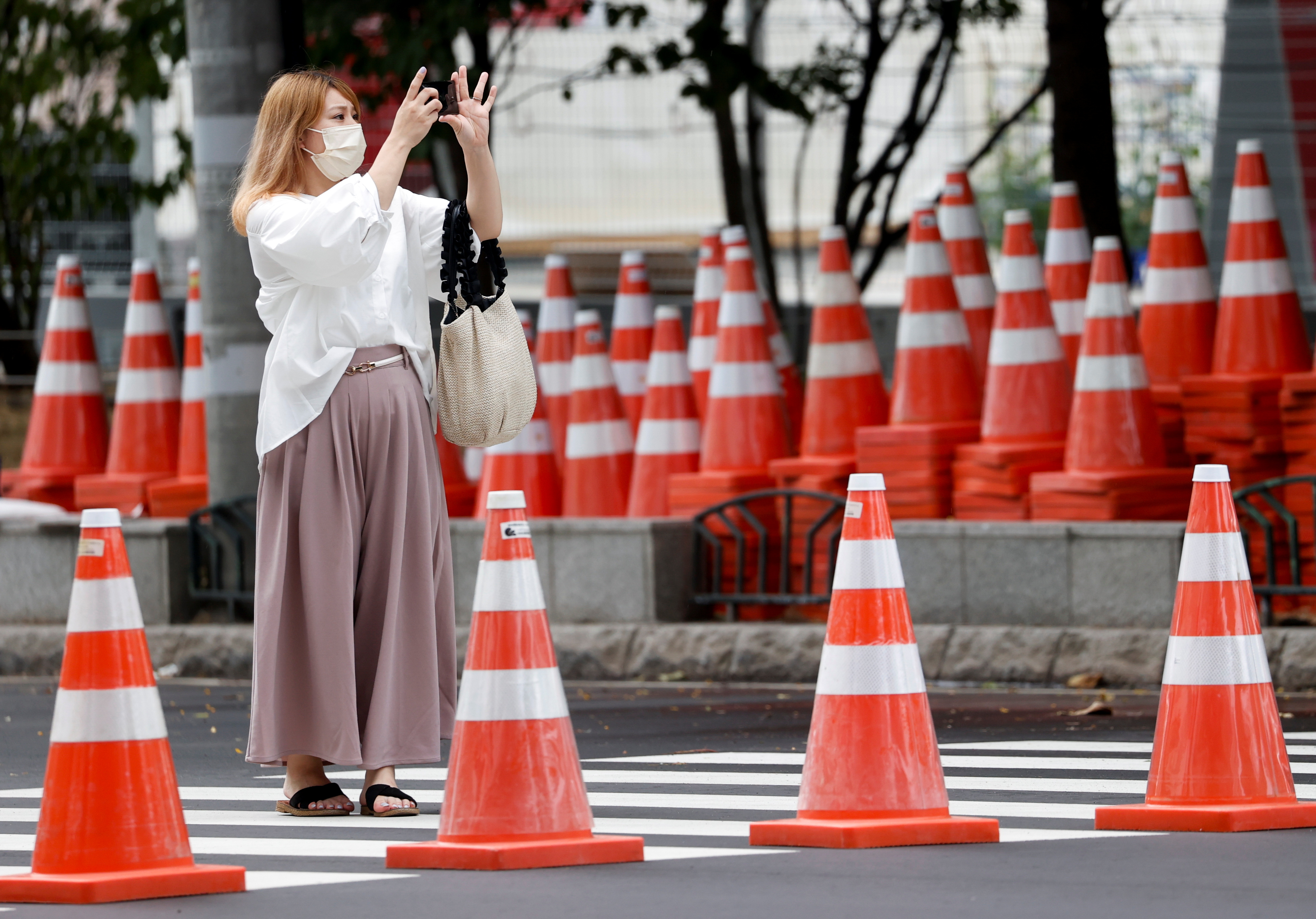 Una mujer toma fotos en la carretera de Tokio previo a la carrera olímpica en Sapporo.