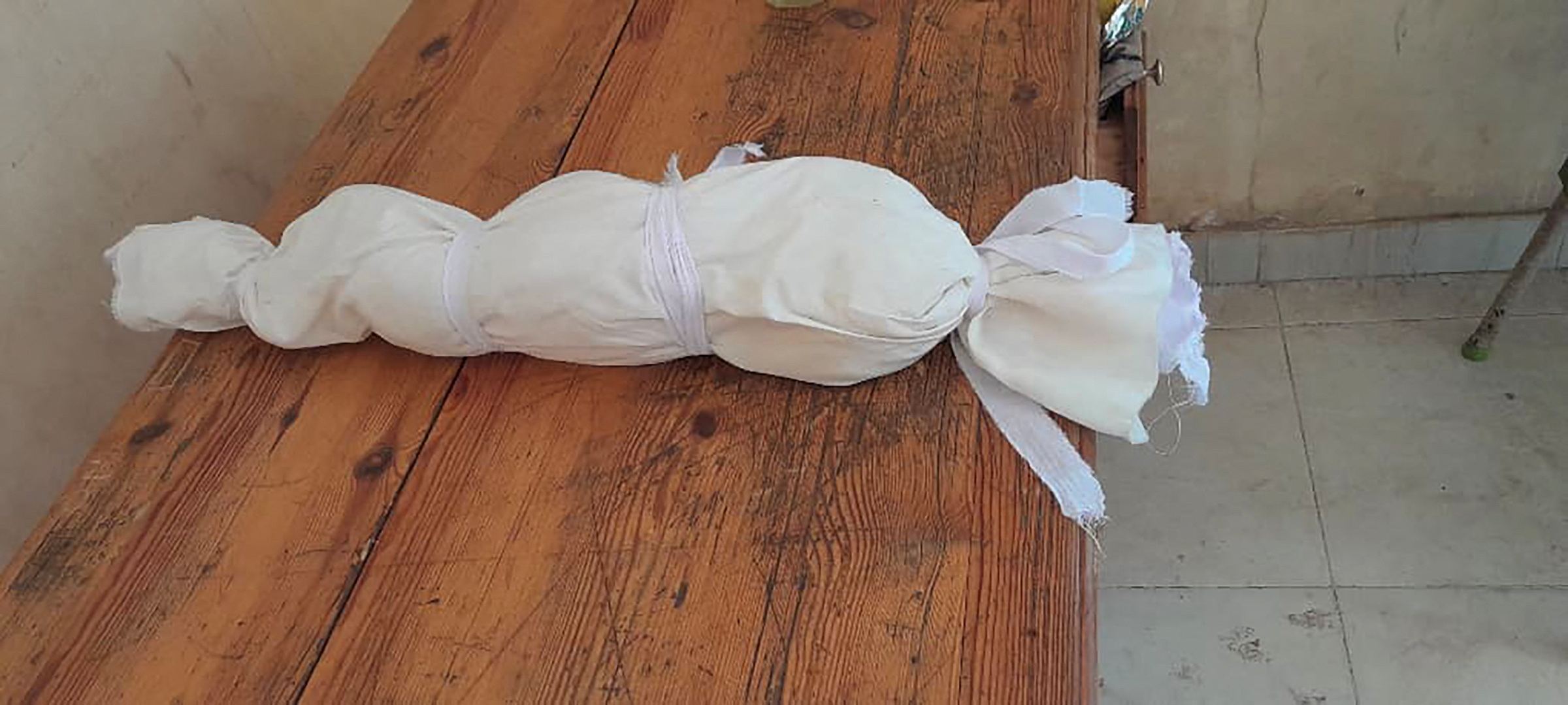 El cuerpo de un bebé yace envuelto en un material blanco después de su muerte en un orfanato en Jartum (Heba Abdullah/Folleto vía REUTERS)