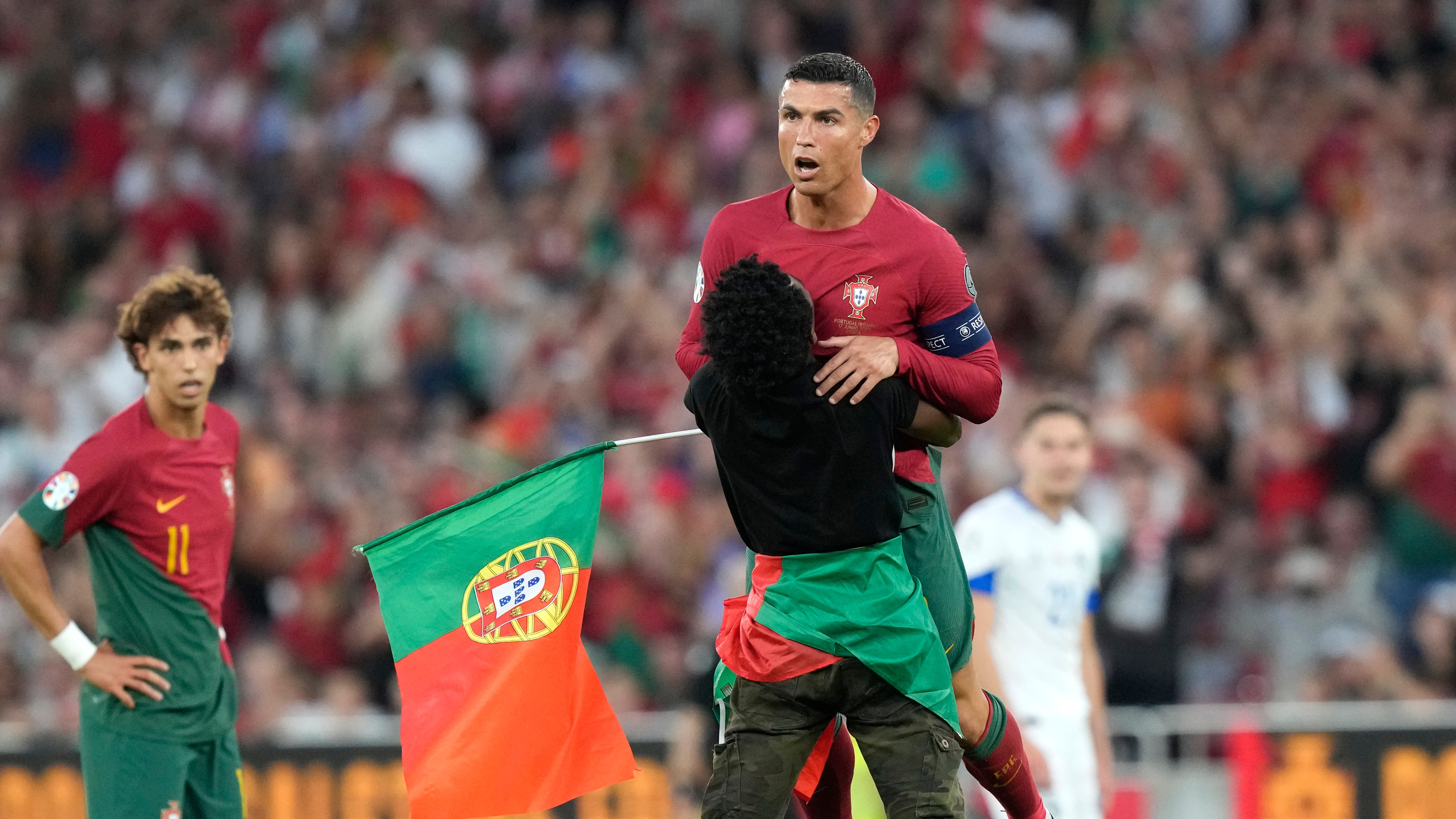 Un individuo que irrumpió en la cancha abraza al astro portugués Cristiano Ronaldo durante el partido contra Bosnia y Herzegovina por las eliminatorias de la Eurocopa, el sábado 17 de junio de 2023, en Lisboa. (AP Foto/Armando Franca)