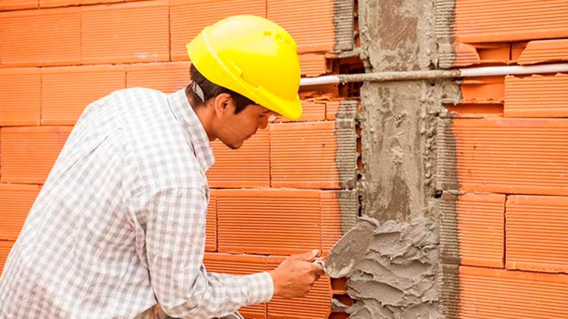 Cuchara en mano y mezcla para asegurar una buena colocación de los ladrillos termoeficientes en la pared