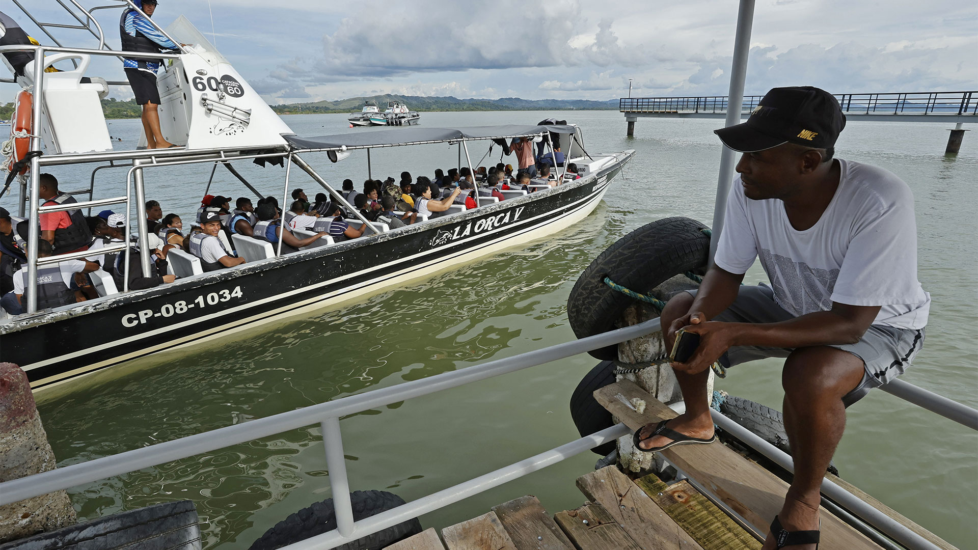 A man observes a boat that leaves with migrants towards the border with Panama (EFE/Mauricio Dueñas Castañeda)