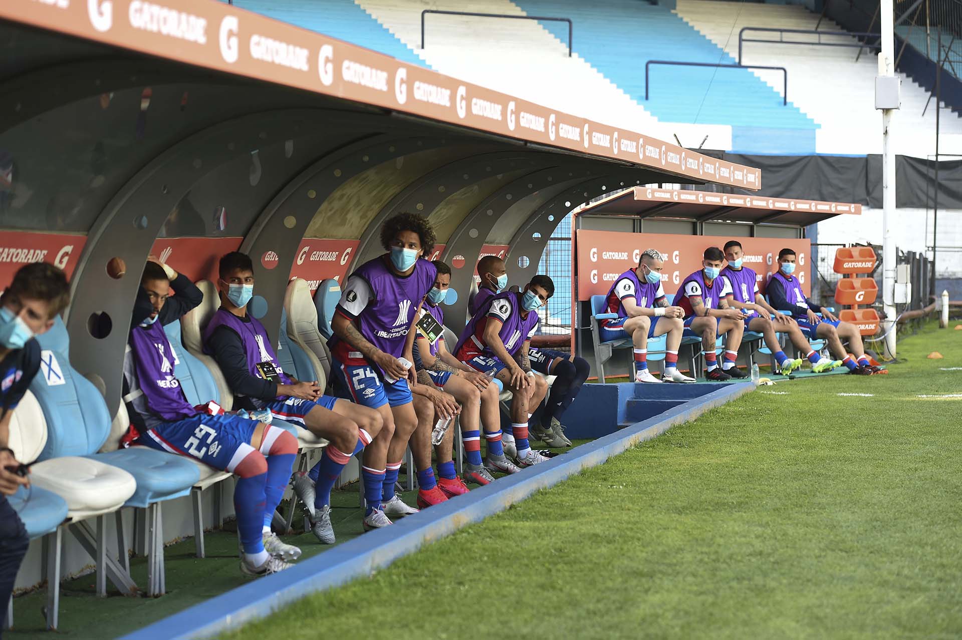 Los bancos de suplentes de Racing y Nacional, con las precauciones por el coronavirus (Marcelo Endelli / POOL / AFP)