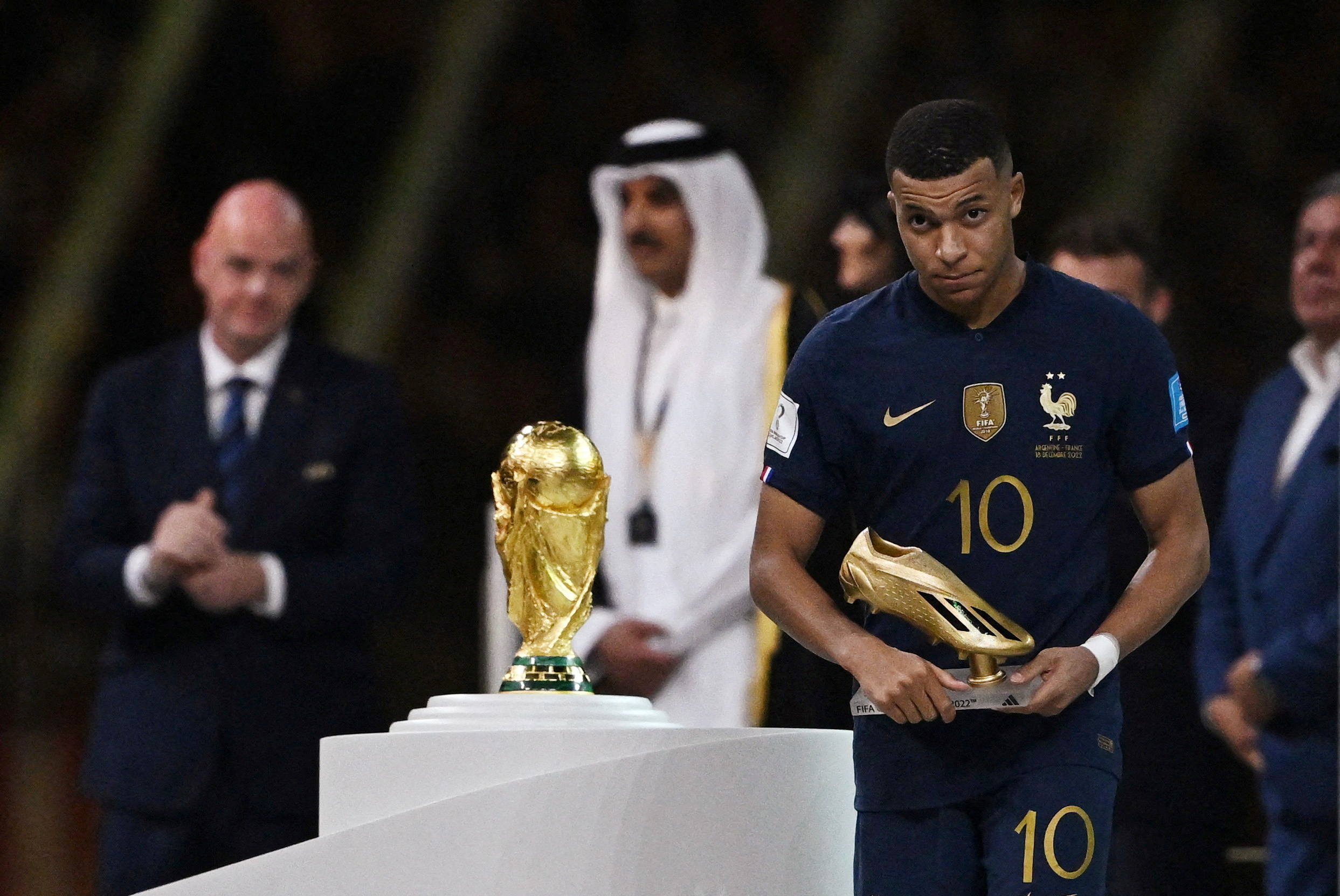 Soccer Football - FIFA World Cup Qatar 2022 - Final - Argentina v France - Lusail Stadium, Lusail, Qatar - December 18, 2022  General view of the World Cup trophy as France's Kylian Mbappe reacts after receiving the Golden Boot award REUTERS/Dylan Martinez     TPX IMAGES OF THE DAY
