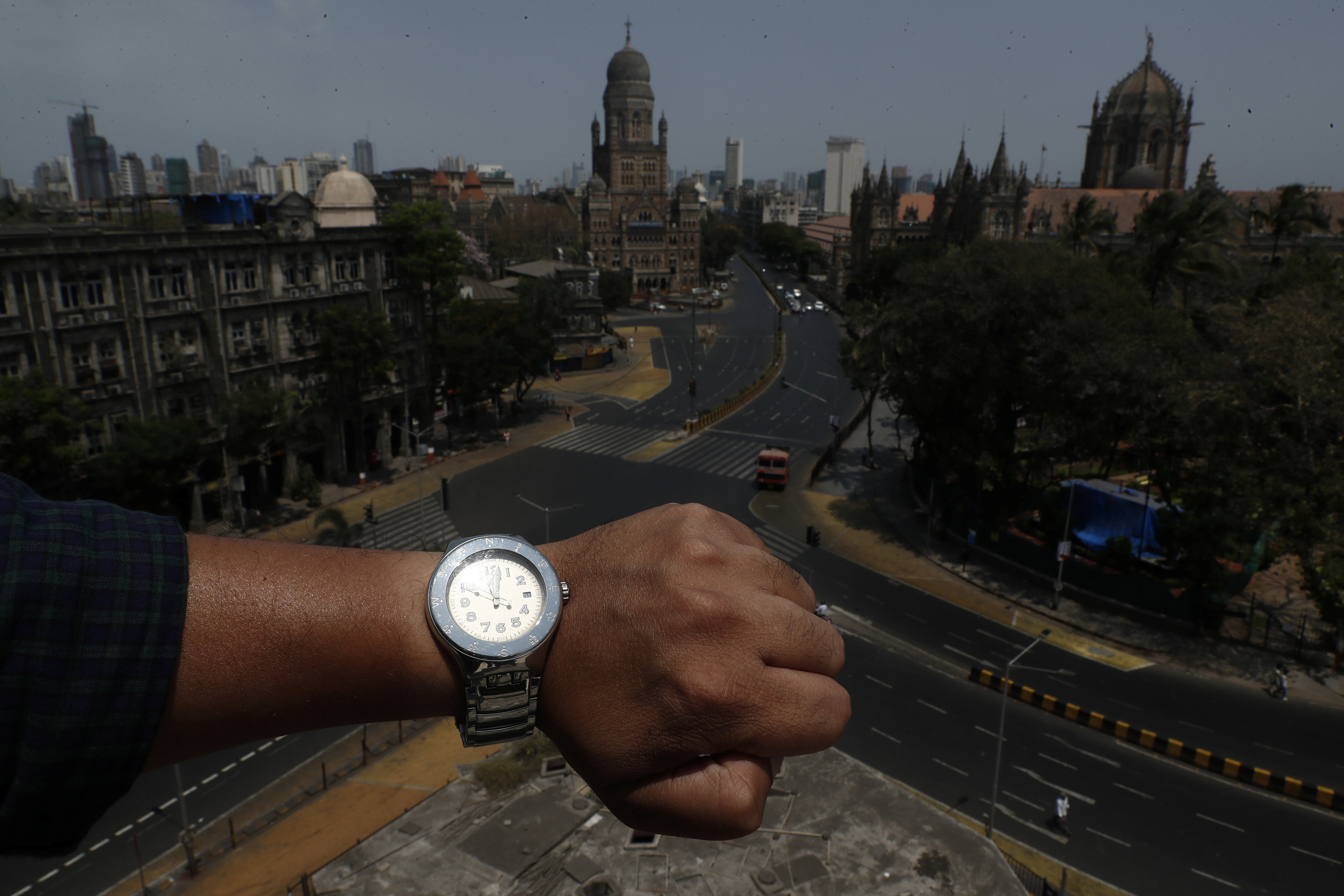 Un fotógrafo muestra en su reloj la hora pico, y la ciudad de Chhatrapati Shivaji Maharaj vacía (REUTERS/Francis Mascarenhas)