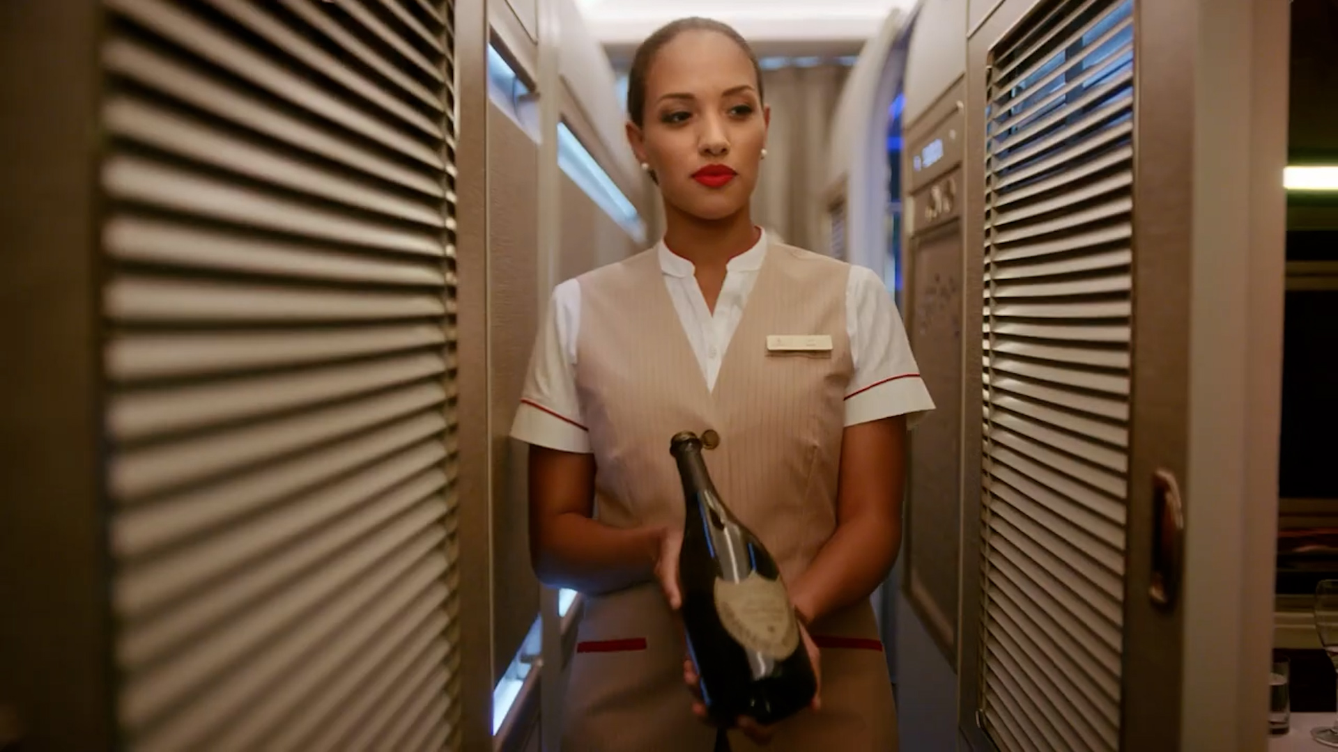 Una azafata de Emirates acerca una botella de Champan Dom Perignon a una cabina de primera clase. (Captura de video Emirates)