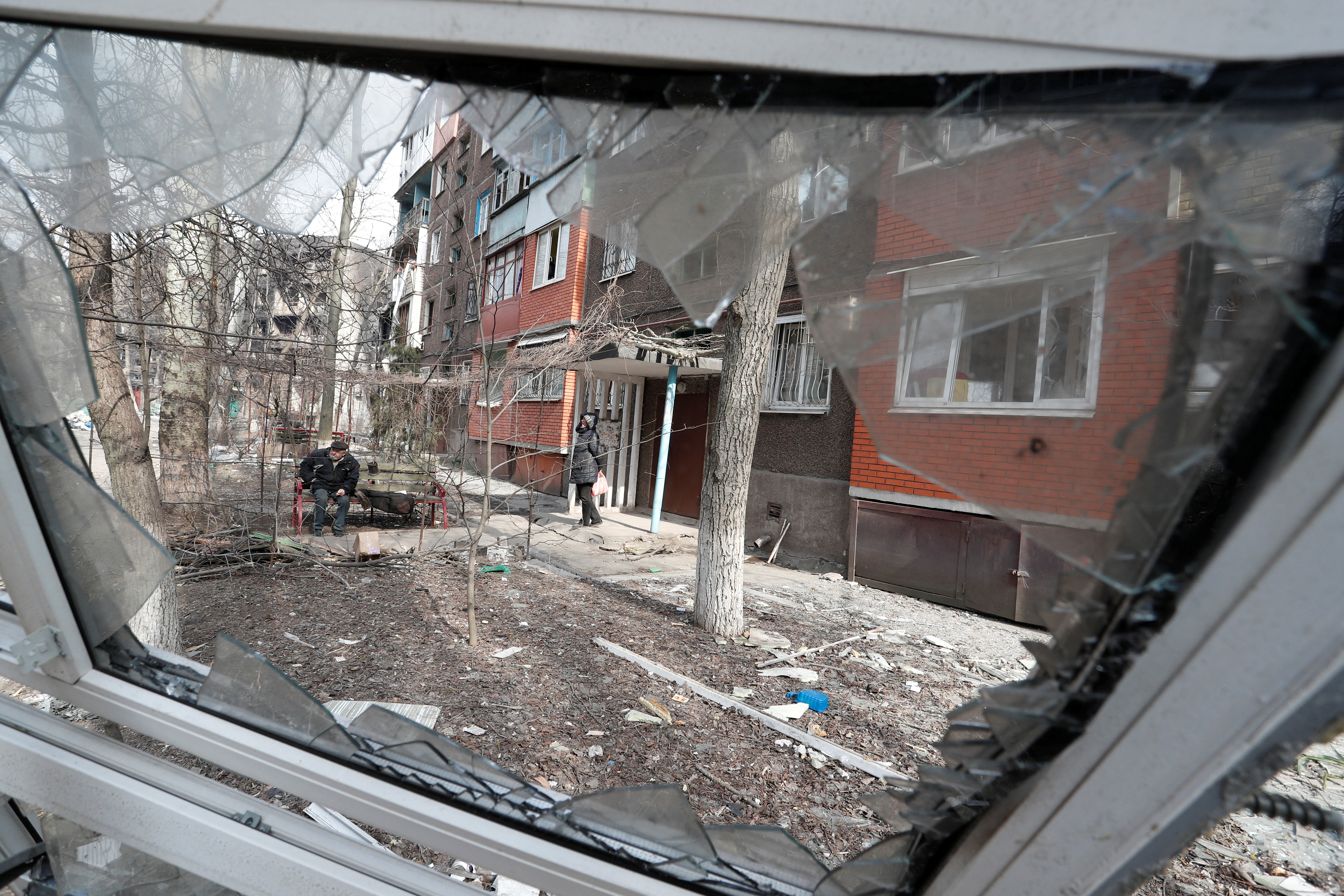 Los residentes locales se reúnen en el patio de un bloque de viviendas dañado en la ciudad sitiada de Mariupol
