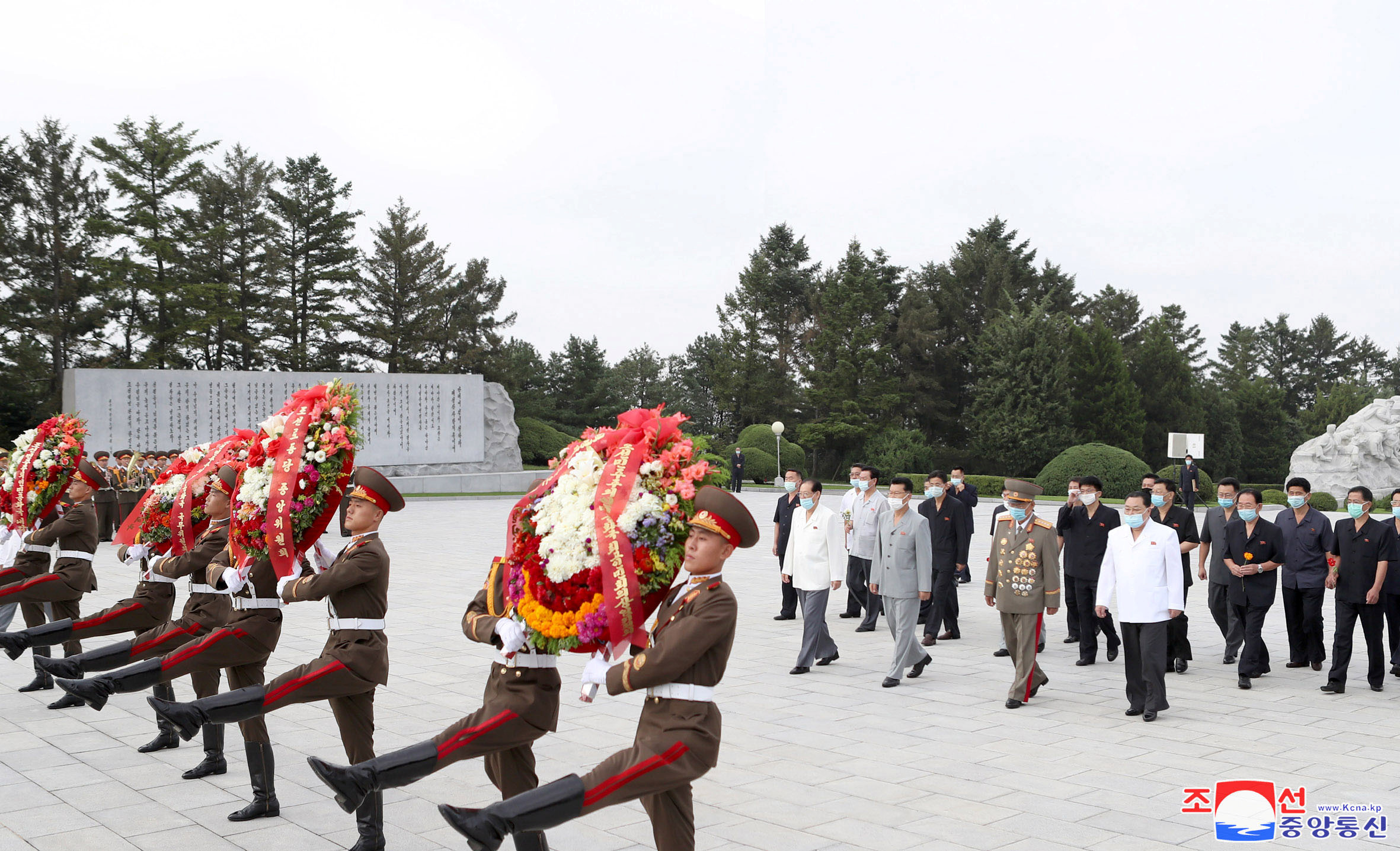 Oficiales norcoreanos caminan frente a las estatuas de Kim Il Sung y Kim Jong Il. KCNA via REUTERS