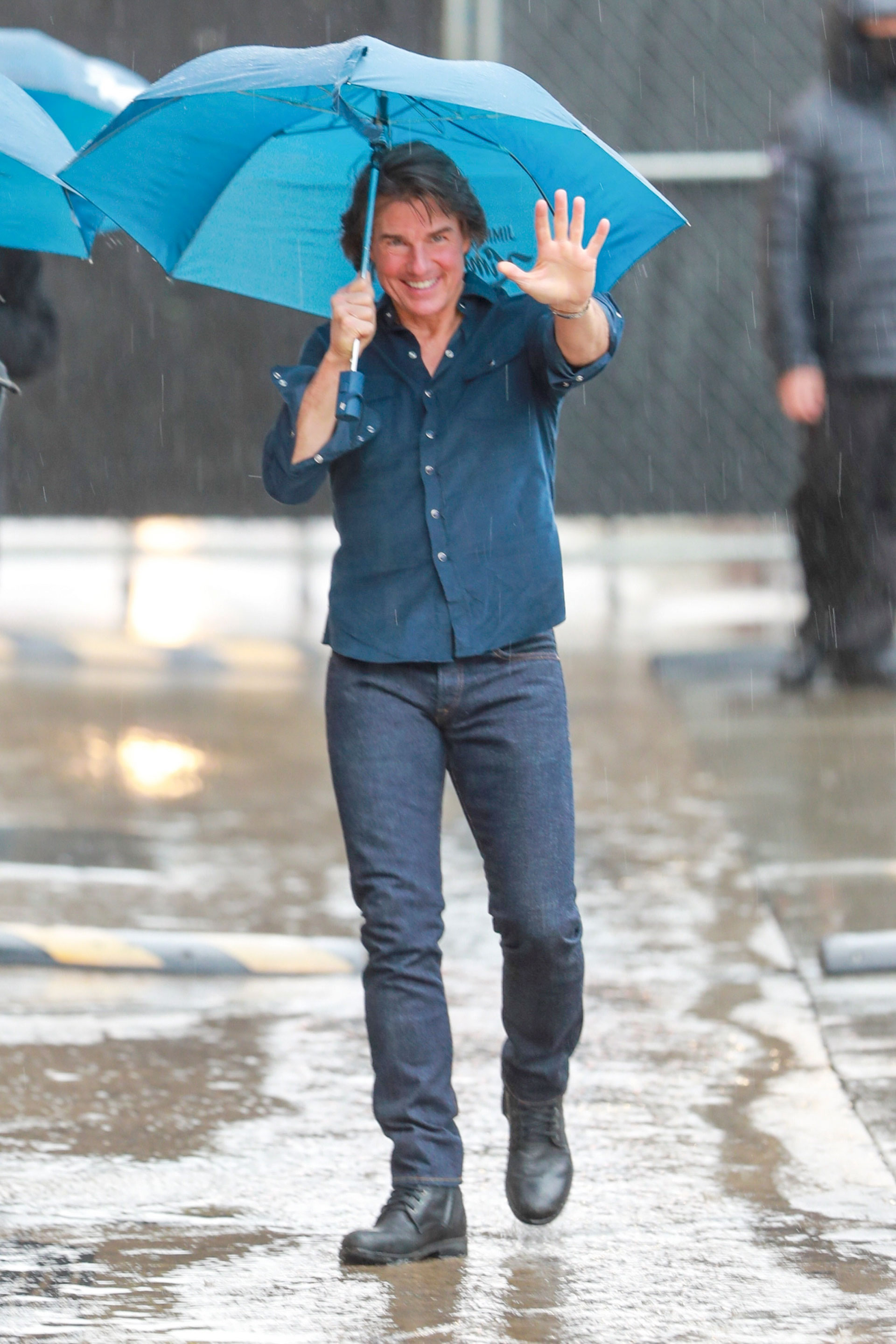 Tom Cruise braved a rainy day to attend Jimmy Kimmel's Hollywood show as a guest.  The actor greeted the fans who came there as well as the local press.  He wore dark pants that he combined with a rolled-up blue shirt and black rubber shoes