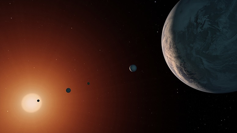 Una ilustración que muestra cómo se vería el sistema TRAPPIST-1 desde un punto de vista cercano al planeta TRAPPIST-1f (derecha). (NASA/JPL-CALTECH)
