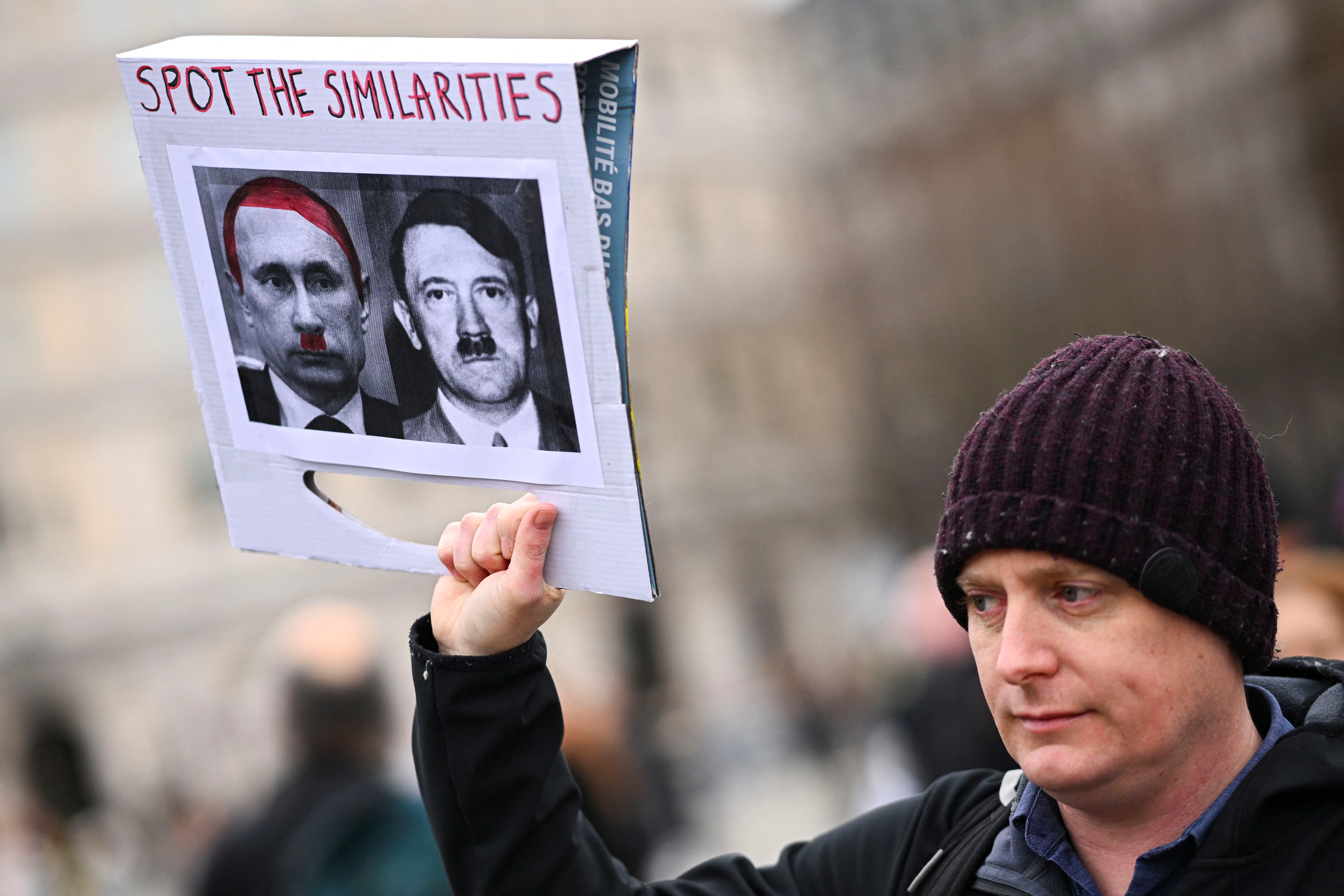 Un hombre sostiene una pancarta que representa al presidente ruso Vladimir Putin y a Adolf Hitler, mientras participa en una protesta contra la invasión rusa de Ucrania, en Trafalgar Square, en Londres, Gran Bretaña el 5 de marzo de 2022 (REUTERS)