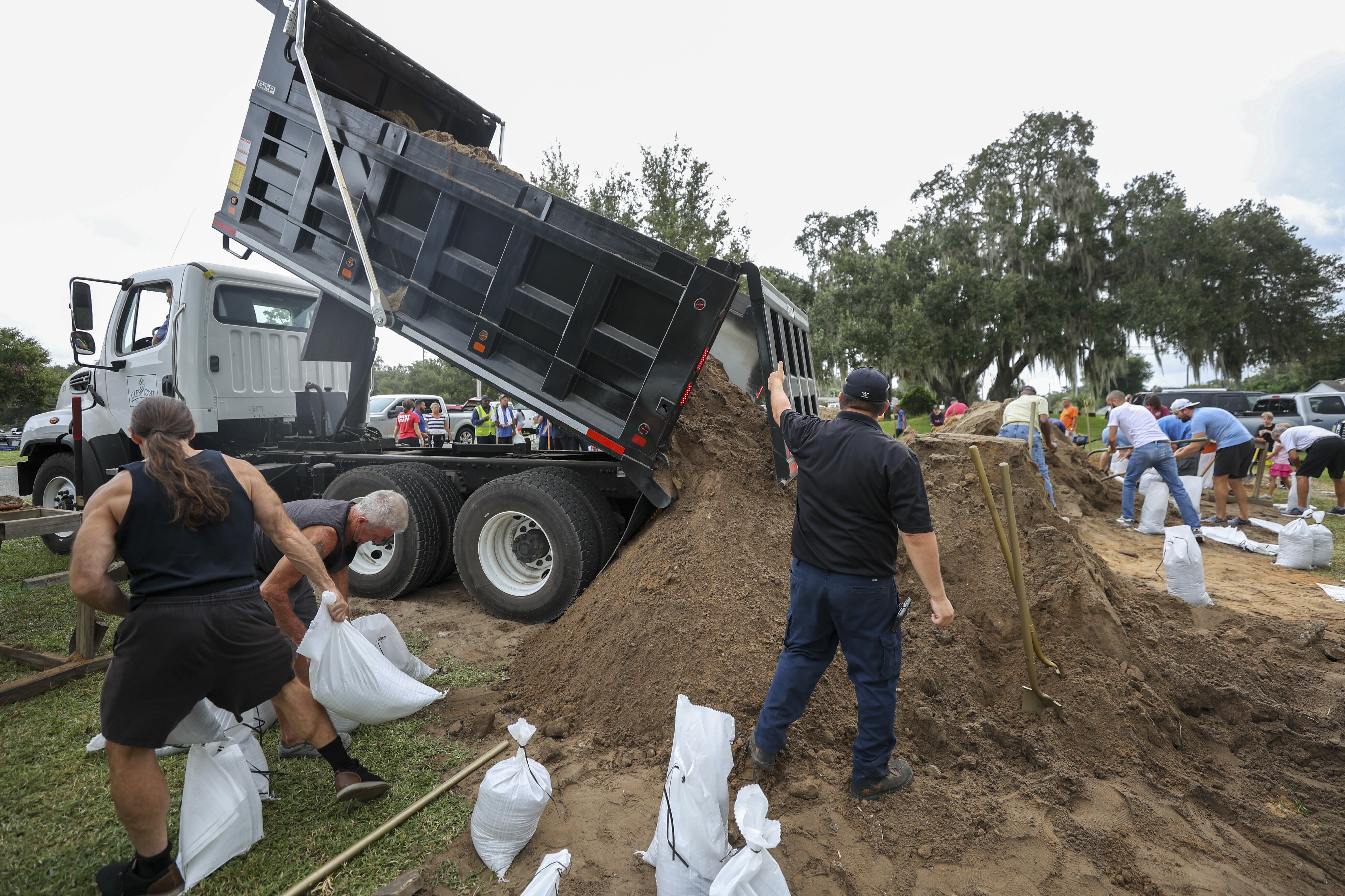 Residentes y trabajadores de la ciudad llenan sacos de arena en West Park en el centro de Clermont, Florida, el martes, en preparación para el huracán Ian. 