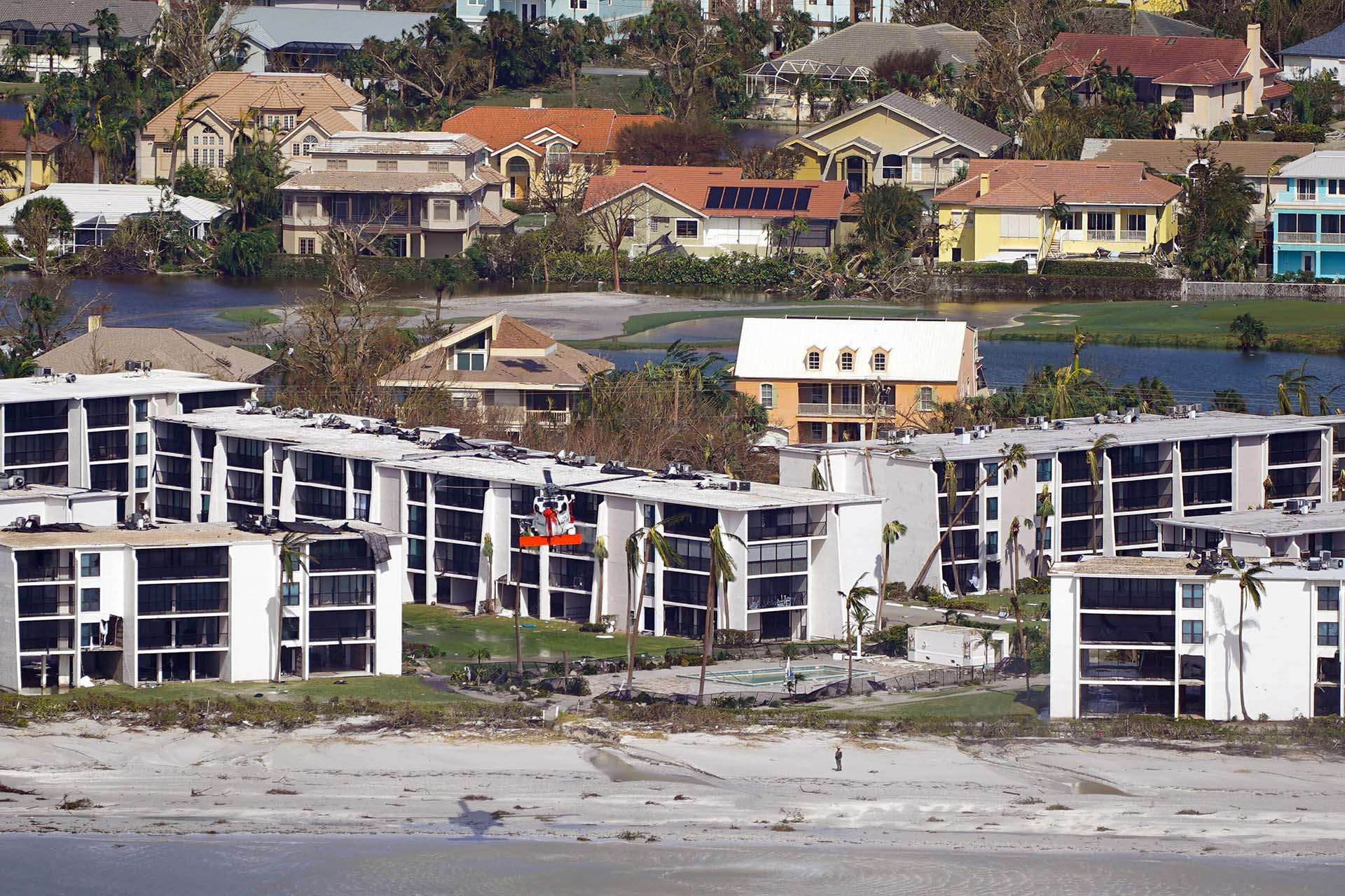 Un helicóptero de la Guardia Costera sobrevuela casas dañadas después del huracán Ian, el jueves 29 de septiembre de 2022, en Sanibel Island, Florida. (AP Photo/Wilfredo Lee)