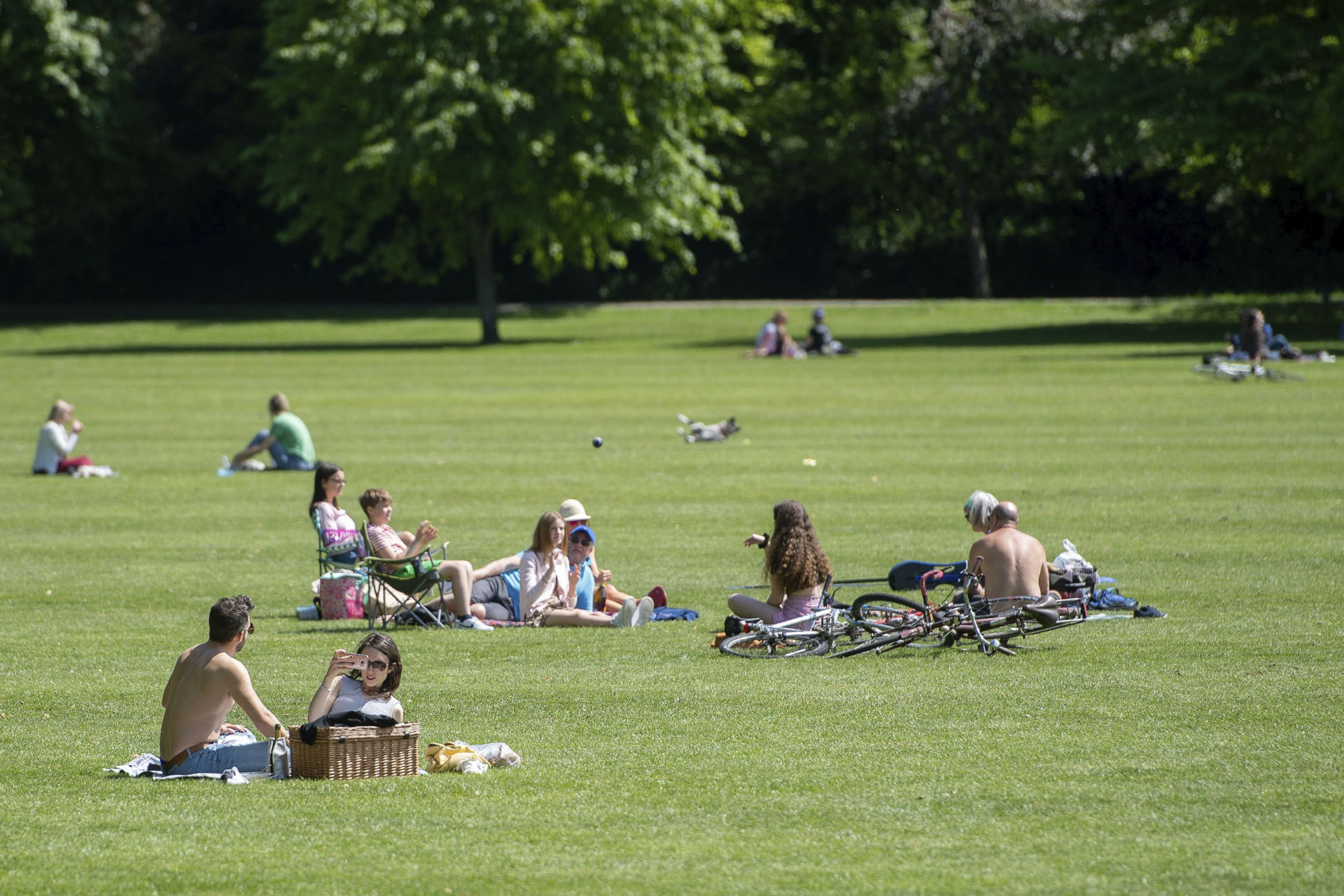 Distancia social entre quienes disfrutan de una soleada tarde en Jesus Green en Cambridge, Inglaterra.