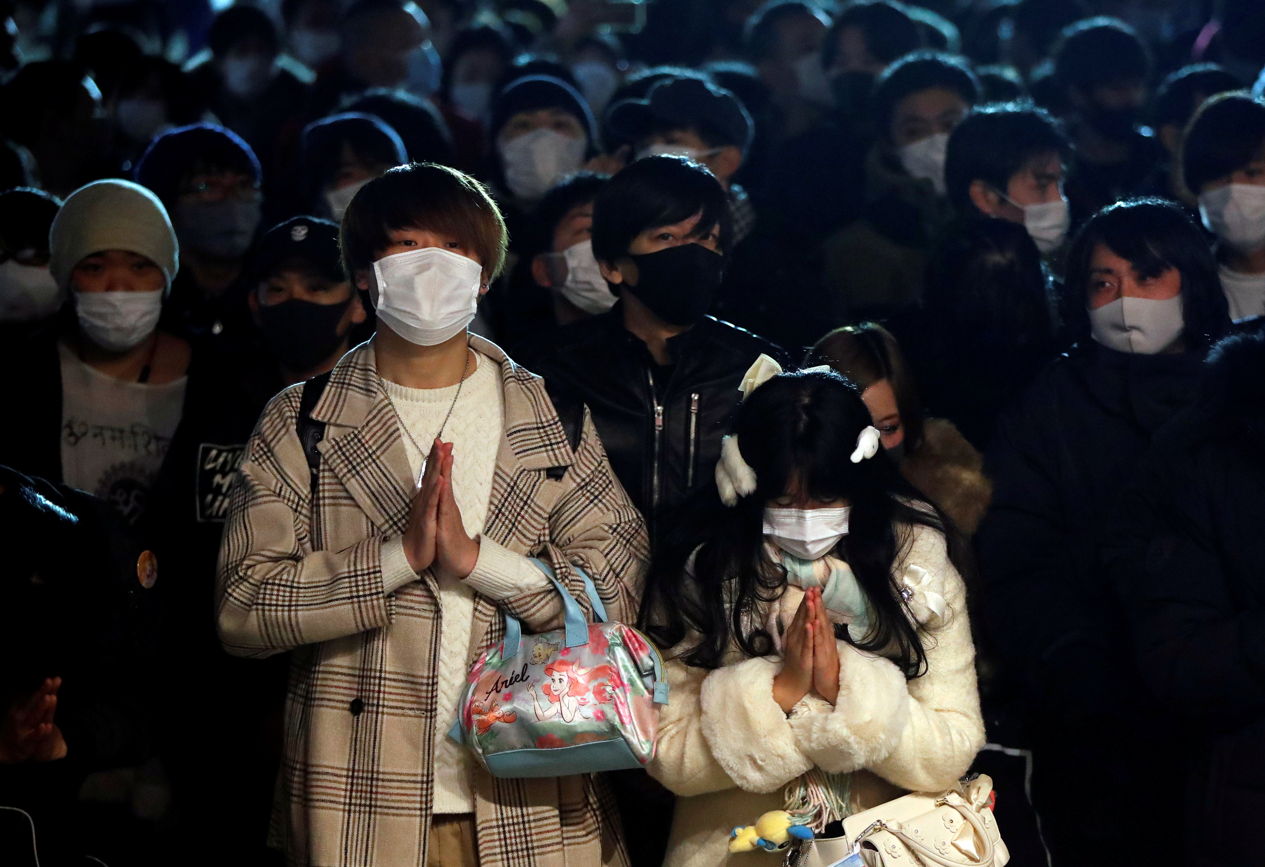 Personas con mascarilla rezan por la llegada del nuevo año (Reuters/ Issei Kato)