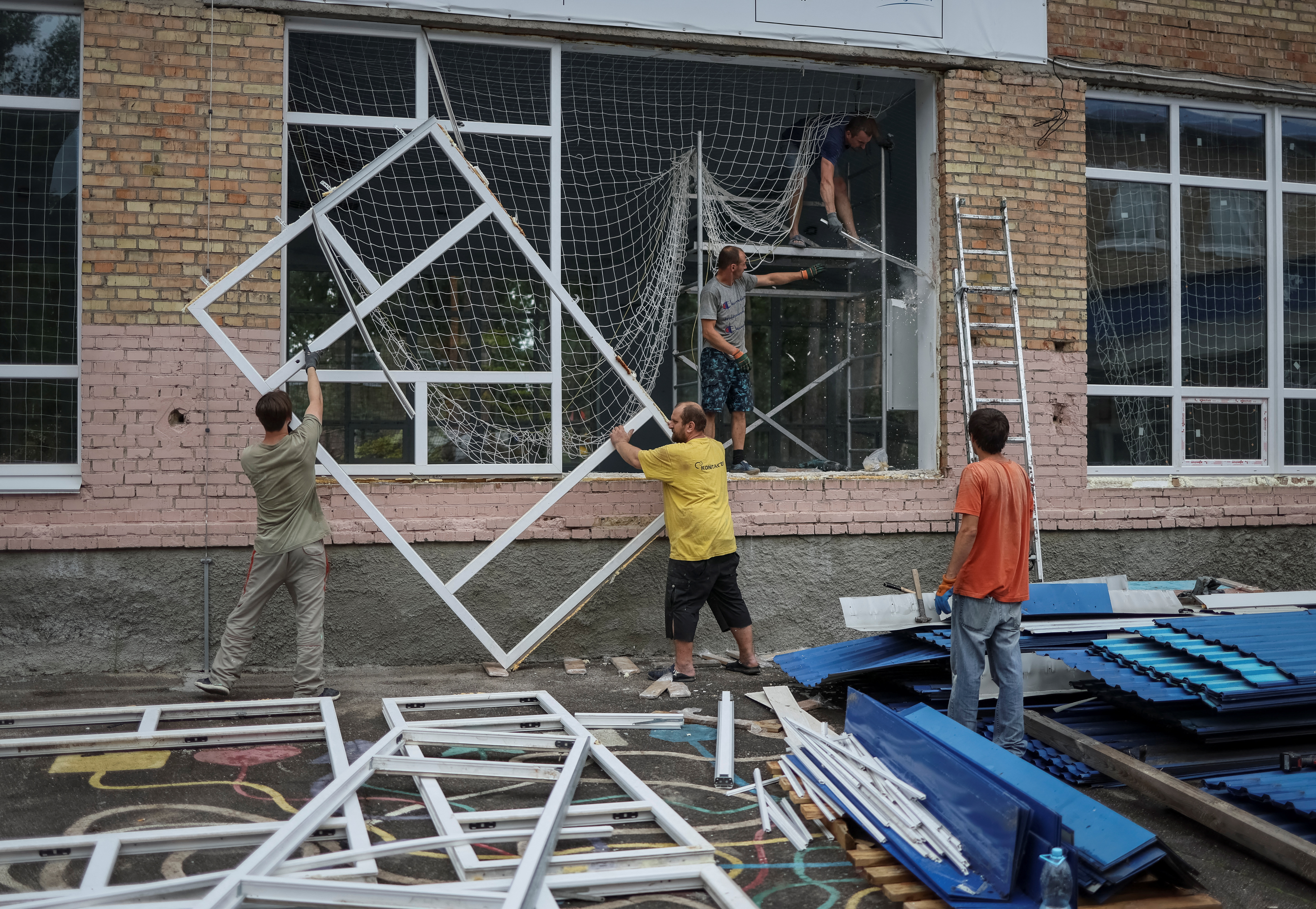 Los trabajadores reemplazan las ventanas que explotaron durante un ataque de artillería rusa en una escuela en la ciudad de Irpin, región de Kyiv, Ucrania, 10 de agosto de 2022. REUTERS/Gleb Garanich