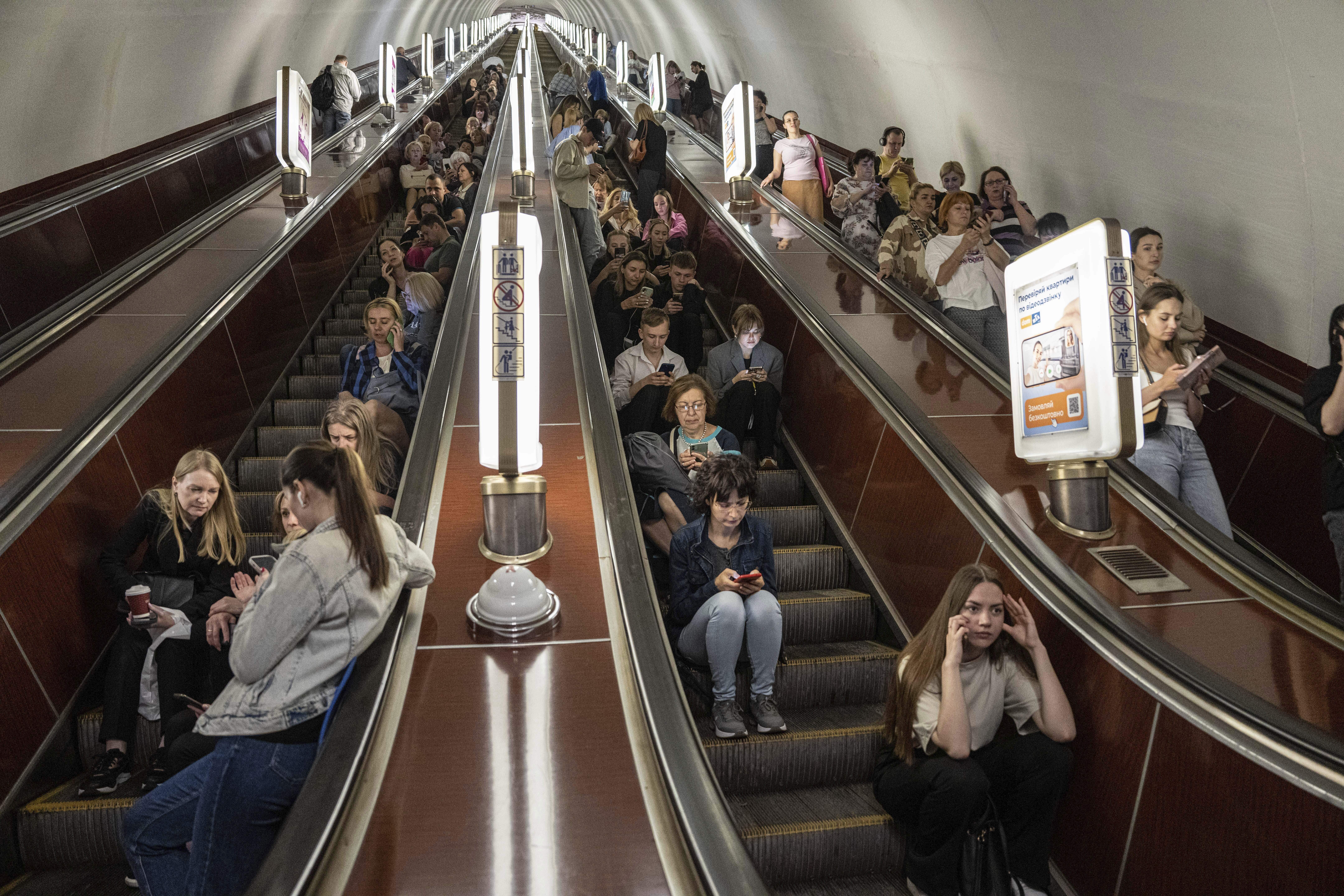 Decenas de personas aguardan en las escaleras eléctricas de una estación del metro usada como refugio durante un ataque con cohetes rusos en Kiev (AP Foto/Evgeniy Maloletka)