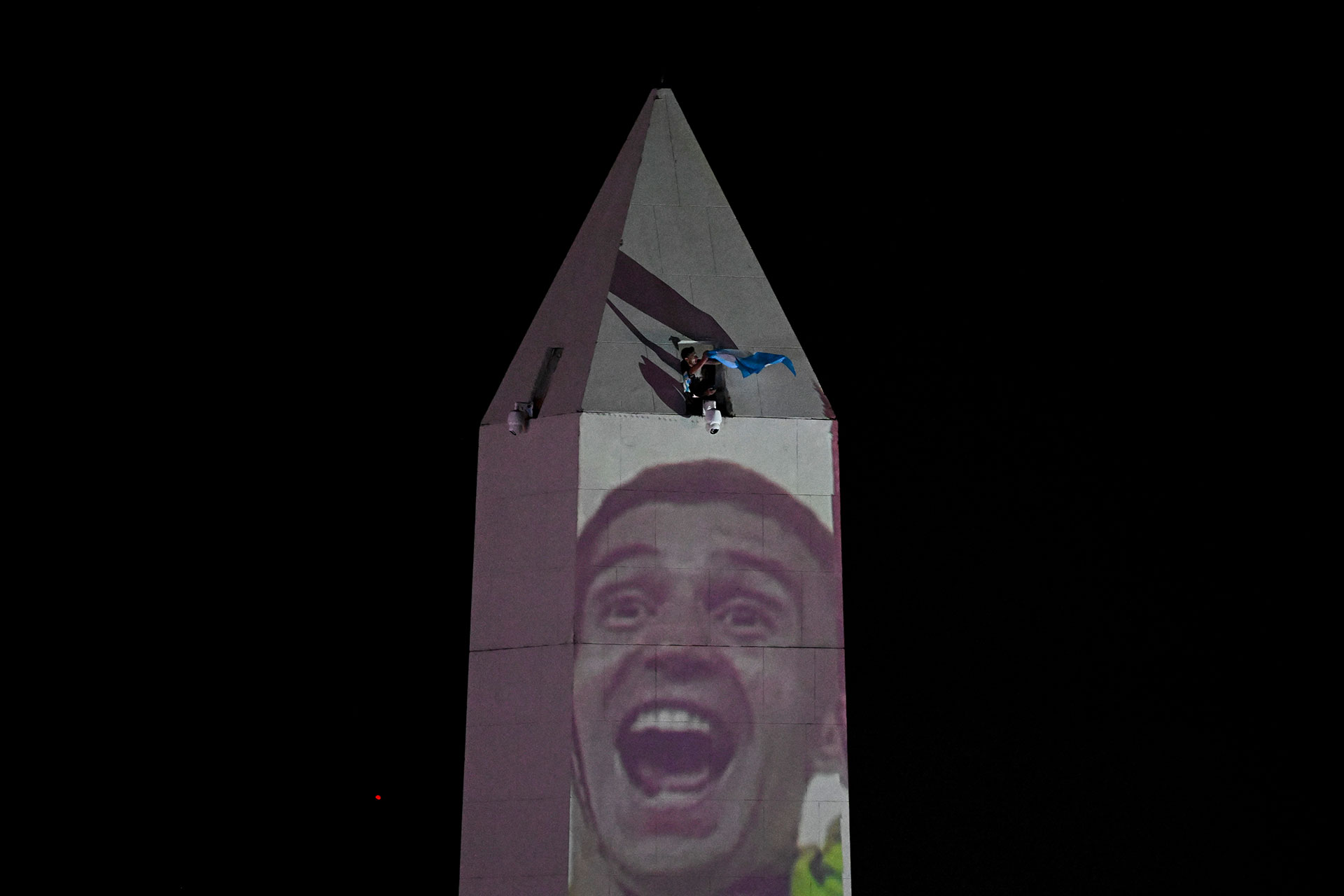 A fan of Argentina celebrates on top of the Obelisk after winning the Qatar 2022 World Cup against France in Buenos Aires on December 18, 2022. (Photo by Luis ROBAYO / AFP)