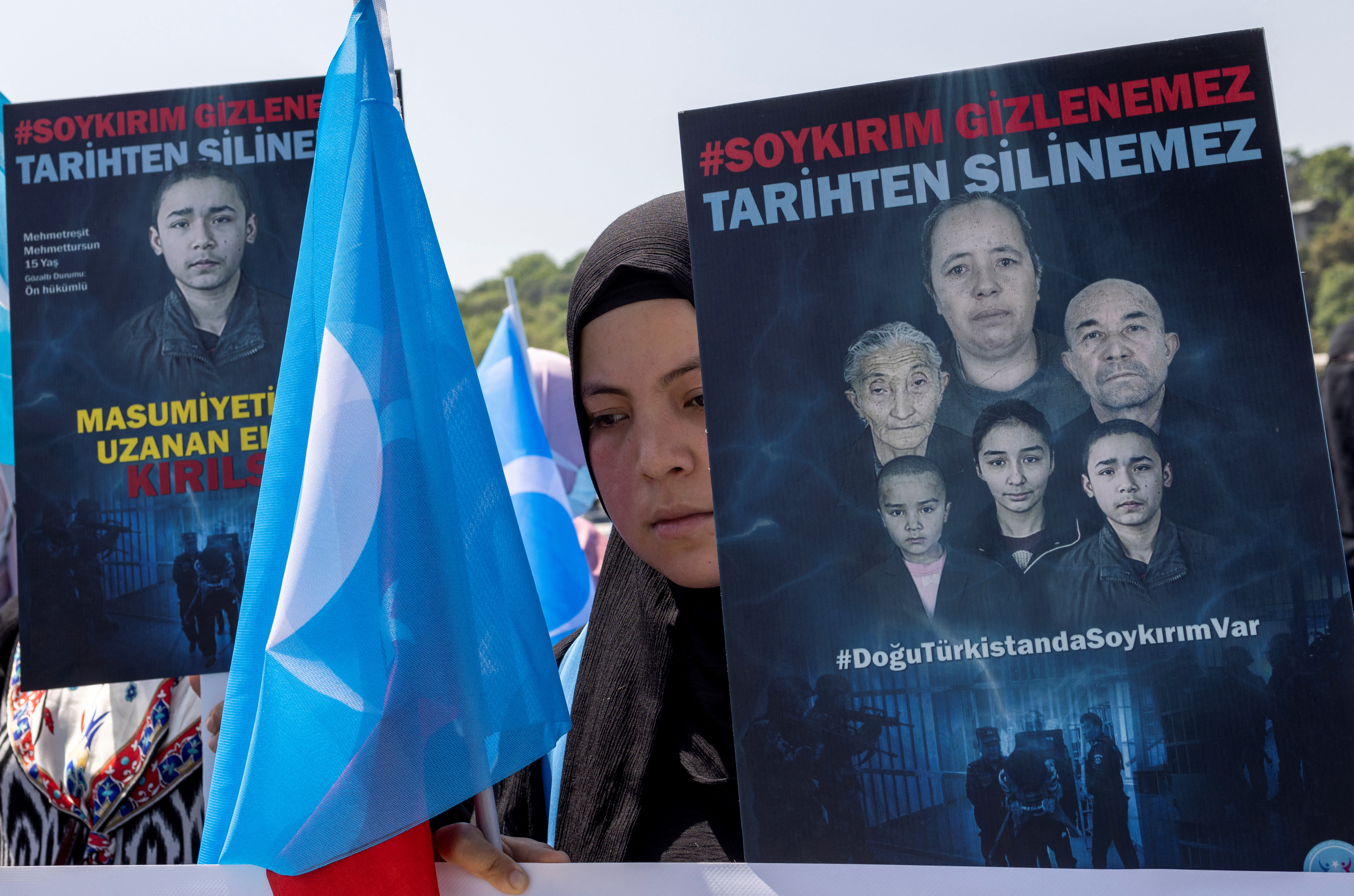 Una mujer de etnia uigur sostiene una bandera del Turquestán Oriental y una pancarta en la que se lee: "El genocidio es indiscutible, no puede ser borrado de la historia" durante una protesta contra China cerca del consulado chino en Estambul, Turquía, el 26 de mayo de 2022(REUTERS/Umit Bektas)