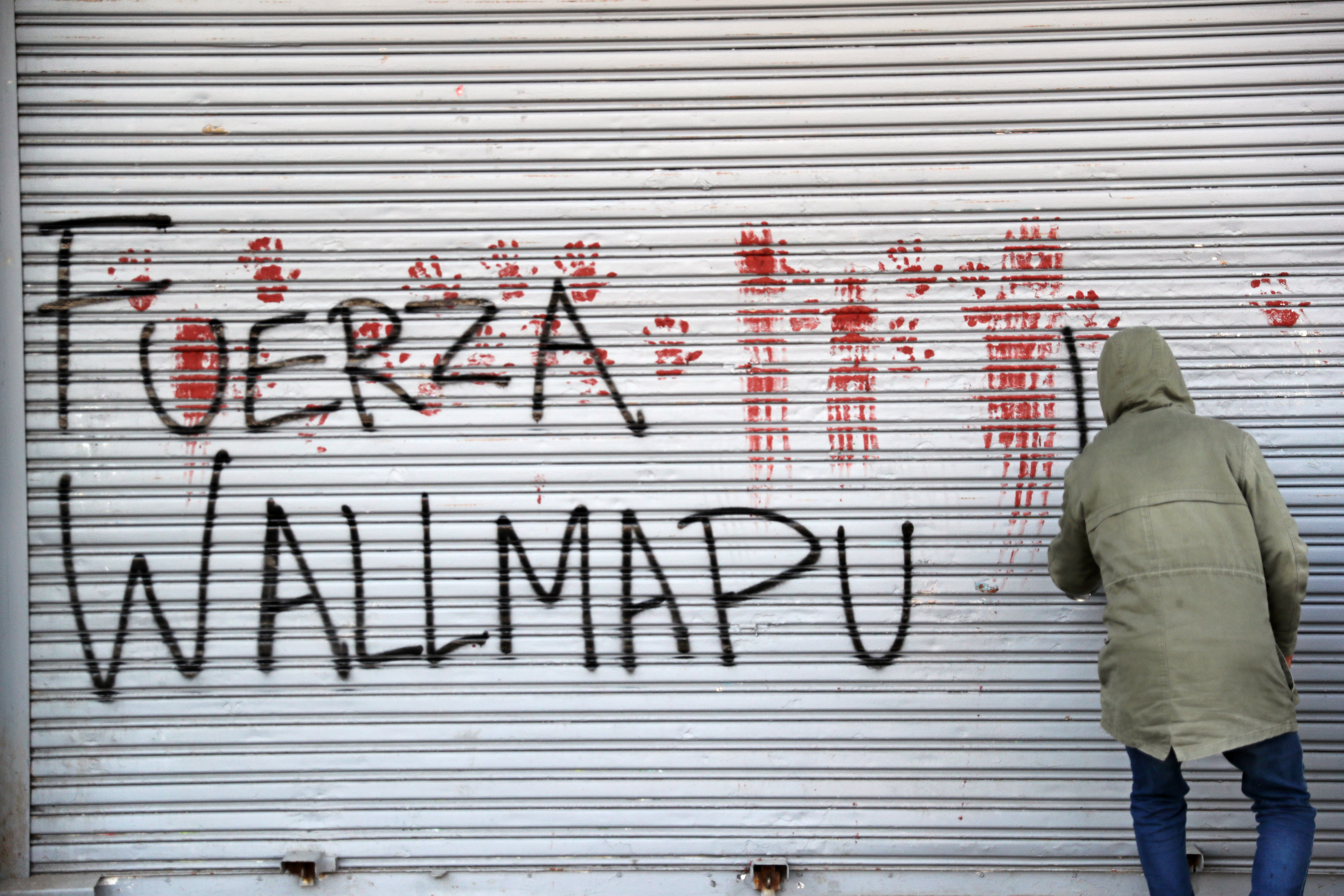 Un manifestante scrive graffiti a sostegno dei Mapuche a Santiago del Cile (Reuters/Ivan Alvarado)