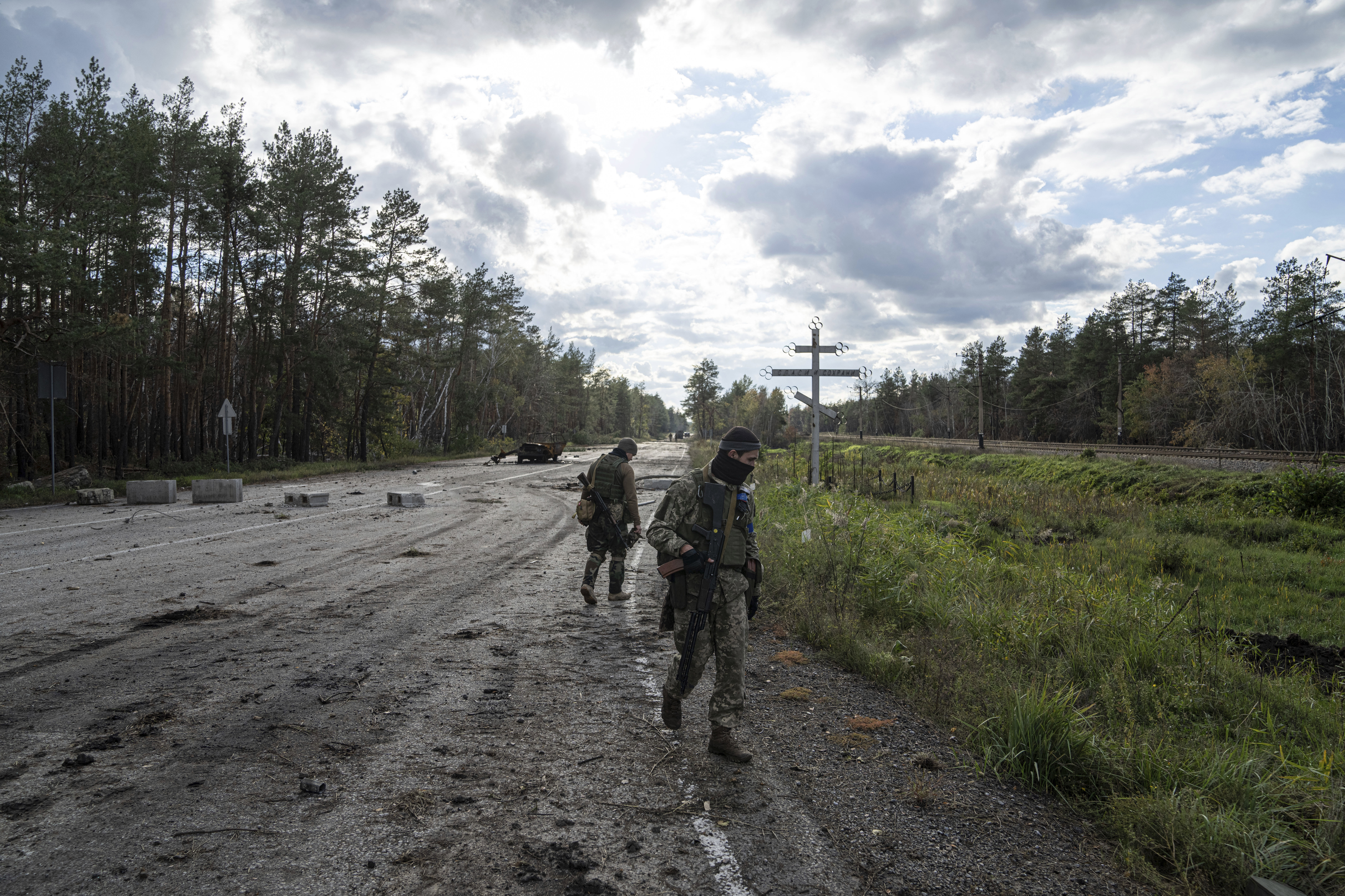 Militares ucranianos caminan por una carretera mientras buscan los cadáveres de sus camaradas en la ciudad recientemente recuperada de Lyman. (Foto AP/Evgeniy Maloletka) 
