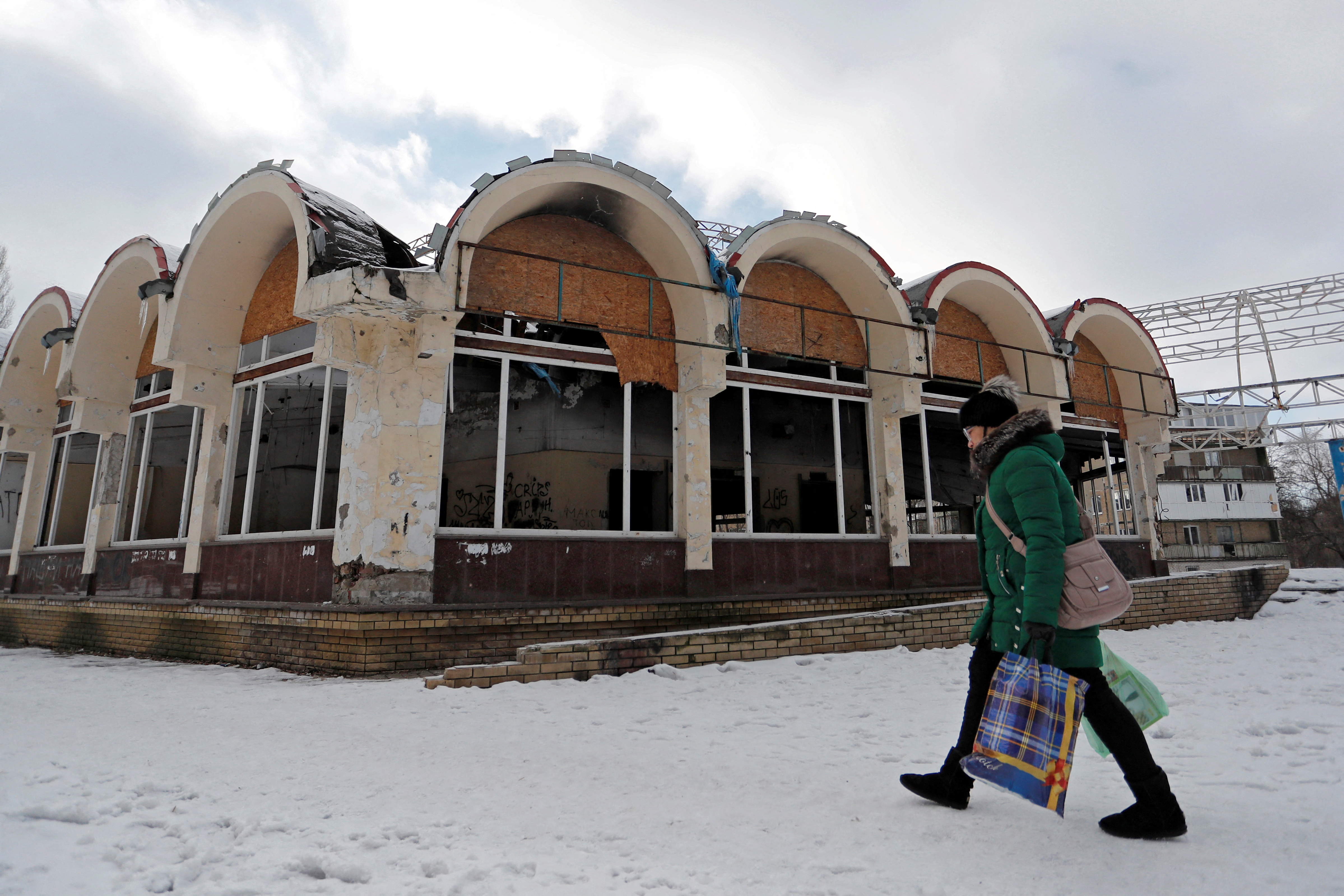 Una mujer pasa frente a una tienda dañada en la ciudad de Donetsk, Ucrania, controlada por los rebeldes, el 5 de febrero de 2022. Foto tomada el 5 de febrero de 2022. (REUTERS/Alexander Ermochenko/Foto de archivo)