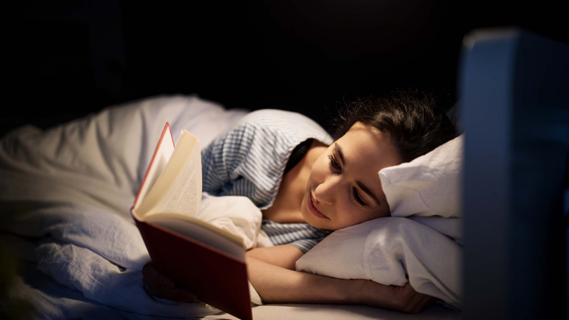 Leer un libro y evitar las pantallas antes de dormir ayuda a conciliar el sueño y combatir el insomnio.