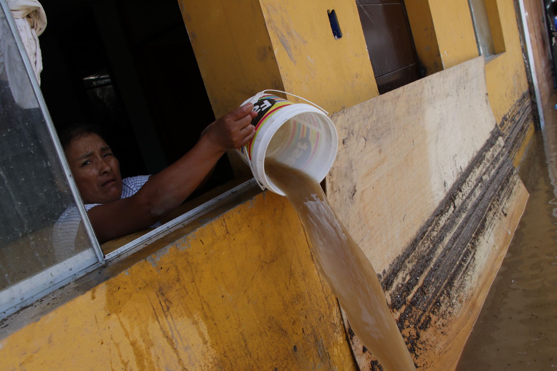 Una mujer trata de sacar el agua empozada en su vivienda tras lluvias torrenciales en el norte del Perú