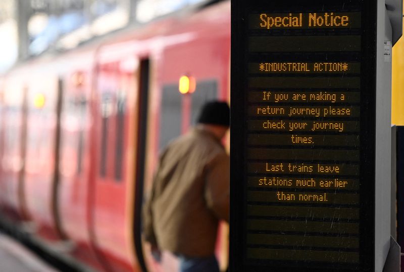 FILE PHOTO: Passengers board a train during a strike by railway workers to demand better wages and conditions, at Waterloo station in London, Britain, December 16, 2022. REUTERS/Toby Melville