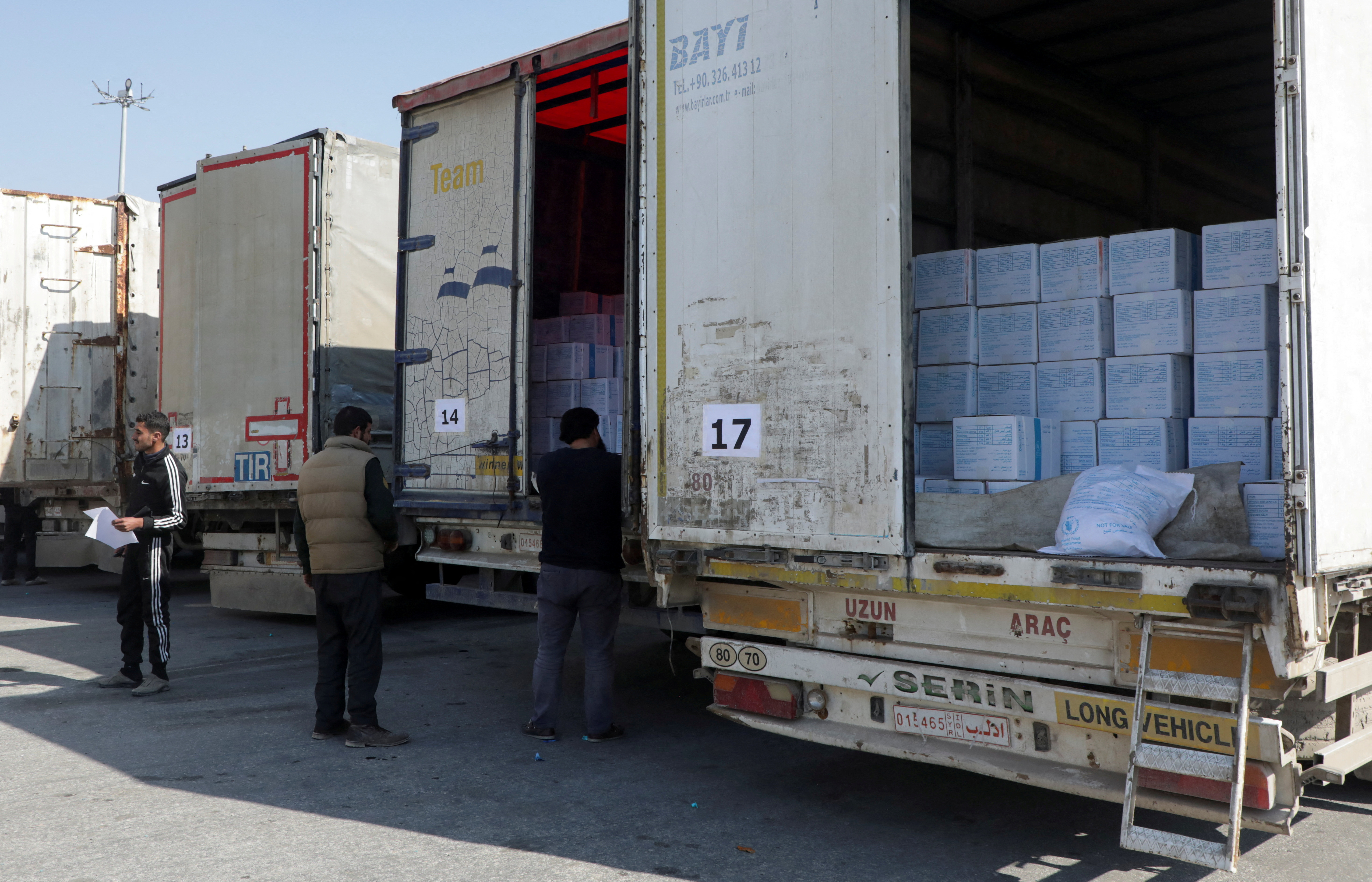 FOTO DE ARCHIVO: Hombres inspeccionan camiones que transportan ayuda del Programa Mundial de Alimentos (PMA) de la ONU, tras un terremoto mortal, en el cruce de Bab al-Hawa, Siria (REUTERS/Mahmoud Hassano)
