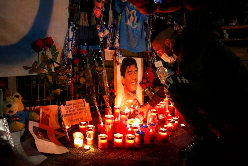 Un hombre enciende una vela en homenaje a la leyenda del fútbol mundial Diego Armando Maradona fuera del Stadio San Paolo en Nápoles, Italia (Reuters)