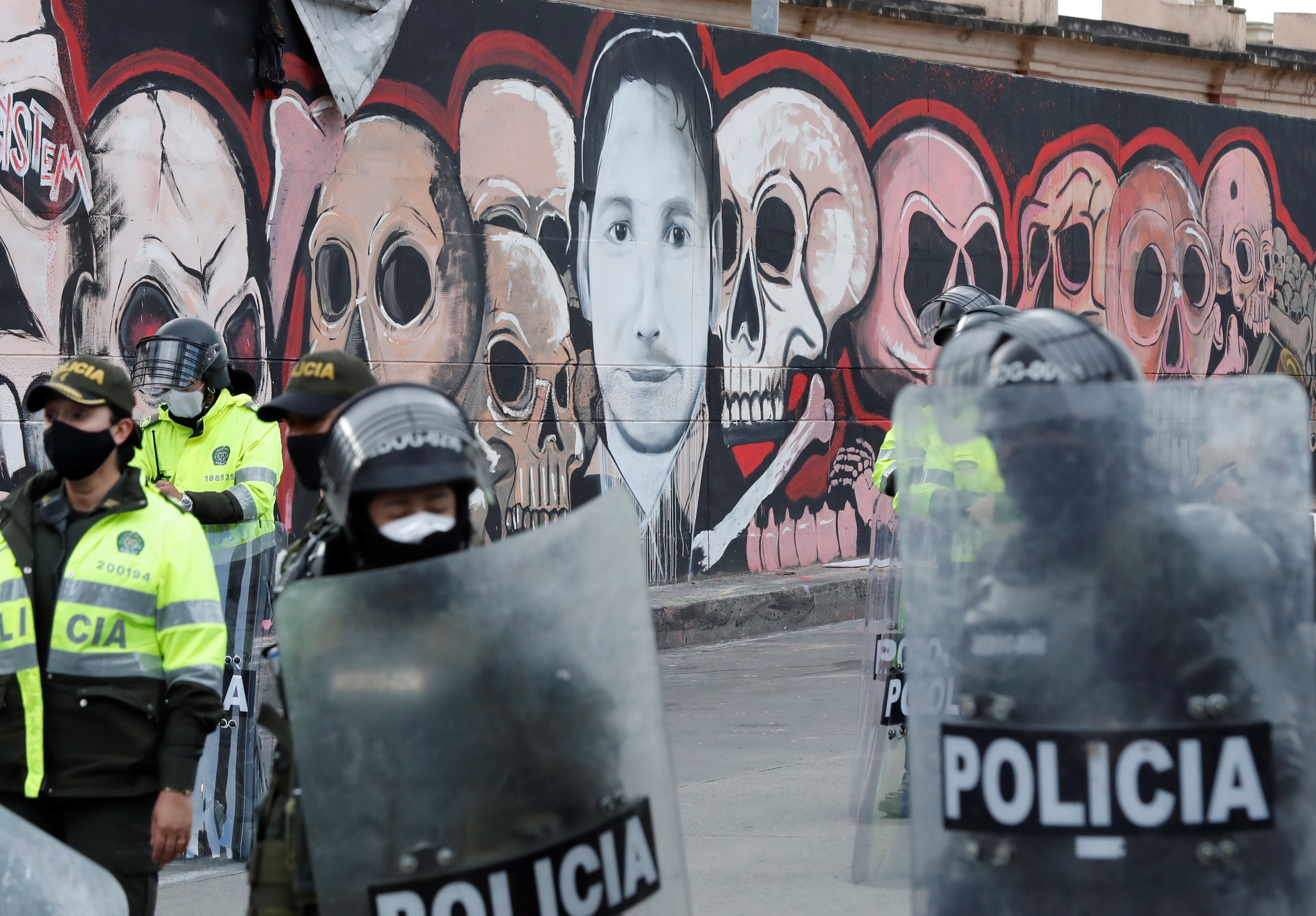 Miembros de la Policía son vistos adelante de un graffiti de Javier Ordóñez, el hombre que murió por el uso excesivo de fuerza policial. EFE/ Mauricio Dueñas Castañeda/Archivo

