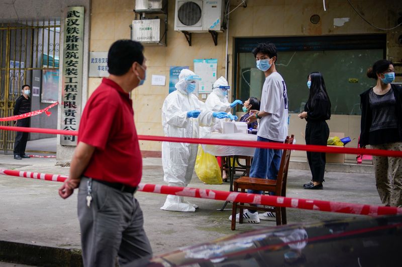 Personal médico en trajes protectores realizan pruebas de ácido nucleico a los residentes de un complejo residencial en Wuhan, en la provincia de Hubei, China (Reuters)