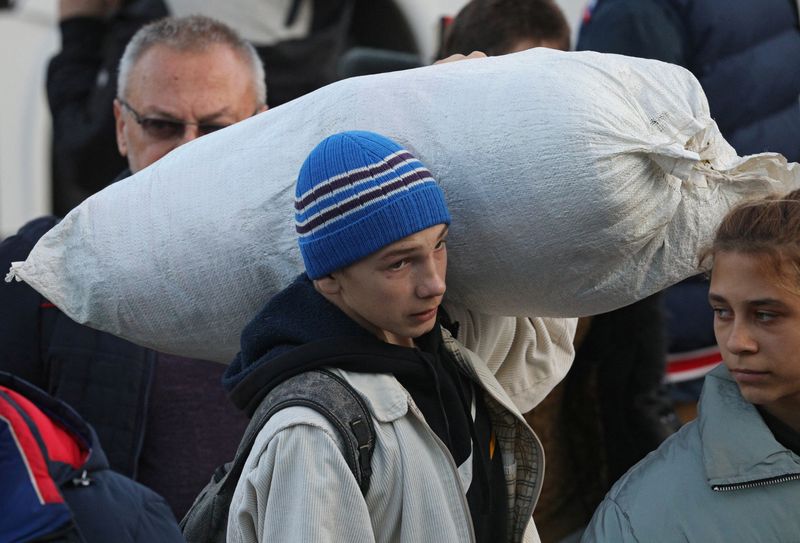 Un joven lleva un saco mientras los civiles evacuados de la región ucraniana de Kherson controlada por Rusia llegan a una estación de tren local (Reuters)