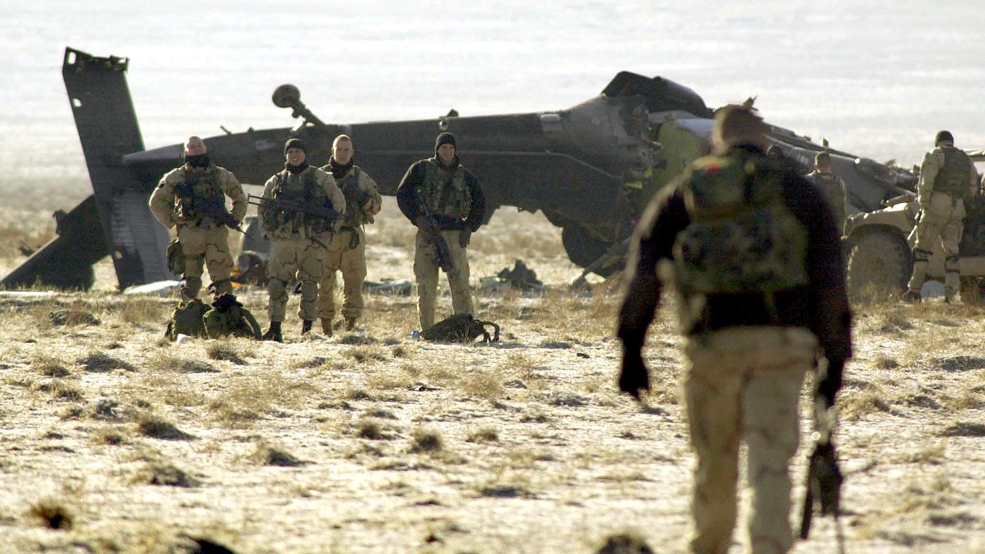 Un soldado estadounidense (derecha) camina hacia el lugar del accidente de un helicóptero BlackHawk, el 31 de enero de 2003, a 12 km (7,5 millas) de Bagram, al norte de Kabul, la principal base aérea estadounidense en Afganistán. Cuatro soldados estadounidenses murieron cuando su helicóptero Blackhawk se estrelló durante una misión de entrenamiento nocturna (AFP PHOTO / Tauseef MUSTAFA)