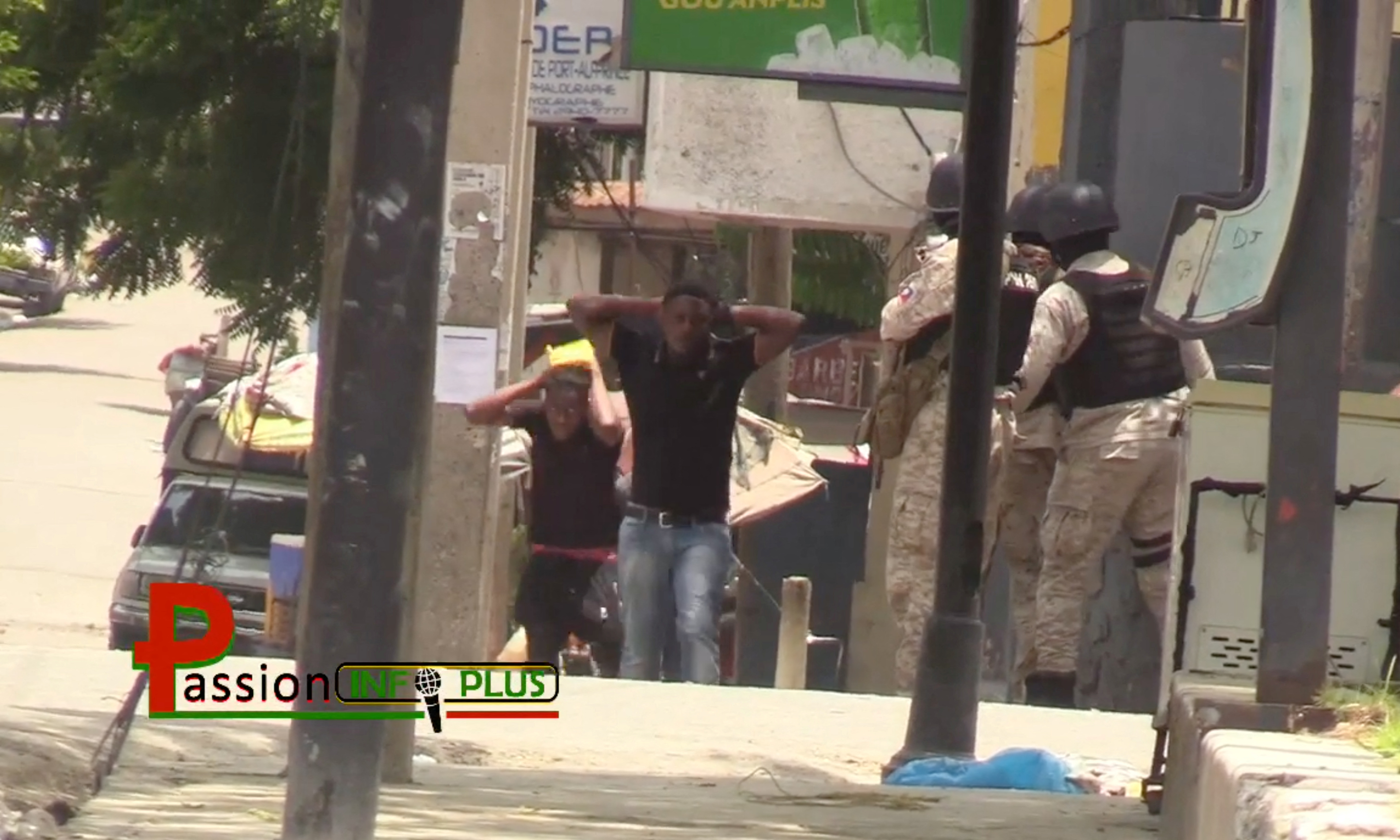 Personas con las manos detrás de la cabeza caminan junto a policías que patrullan la calle en Puerto Príncipe, Haití, el 27 de julio de 2022, en esta imagen fija obtenida de un video de las redes sociales. Cortesía de Passion Info Plus/vía REUTERS 