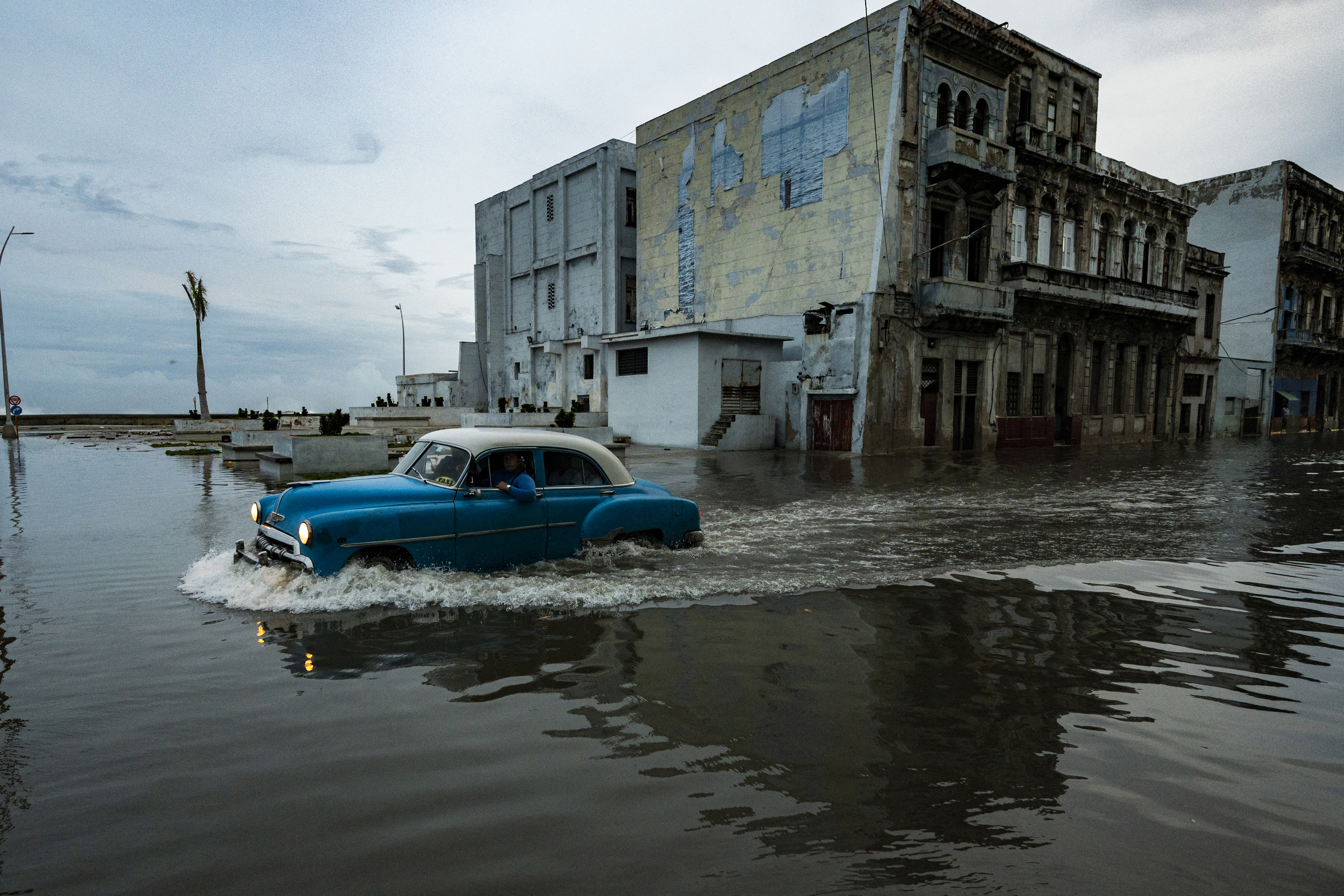 Un viejo automóvil americano pasa por una calle inundada de La Habana. 