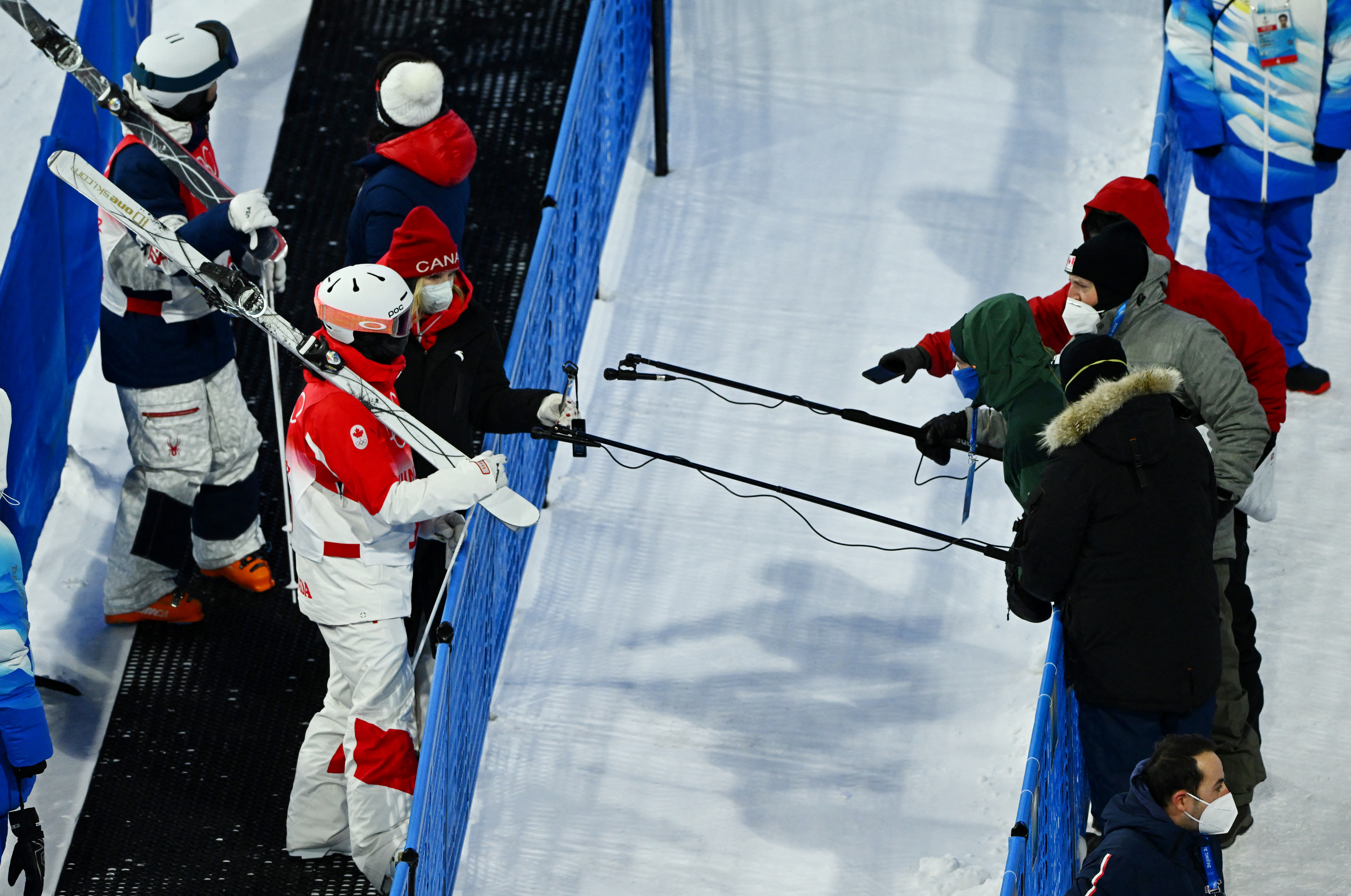 2022 Beijing Olympics - Freestyle Skiing - Men's Moguls - Qualification 2 - Genting Snow Park, Zhangjiakou, China - February 5, 2022.  Members of the media observe social distancing as they conduct an interview with Laurent Dumais of Canada. REUTERS/Dylan Martinez