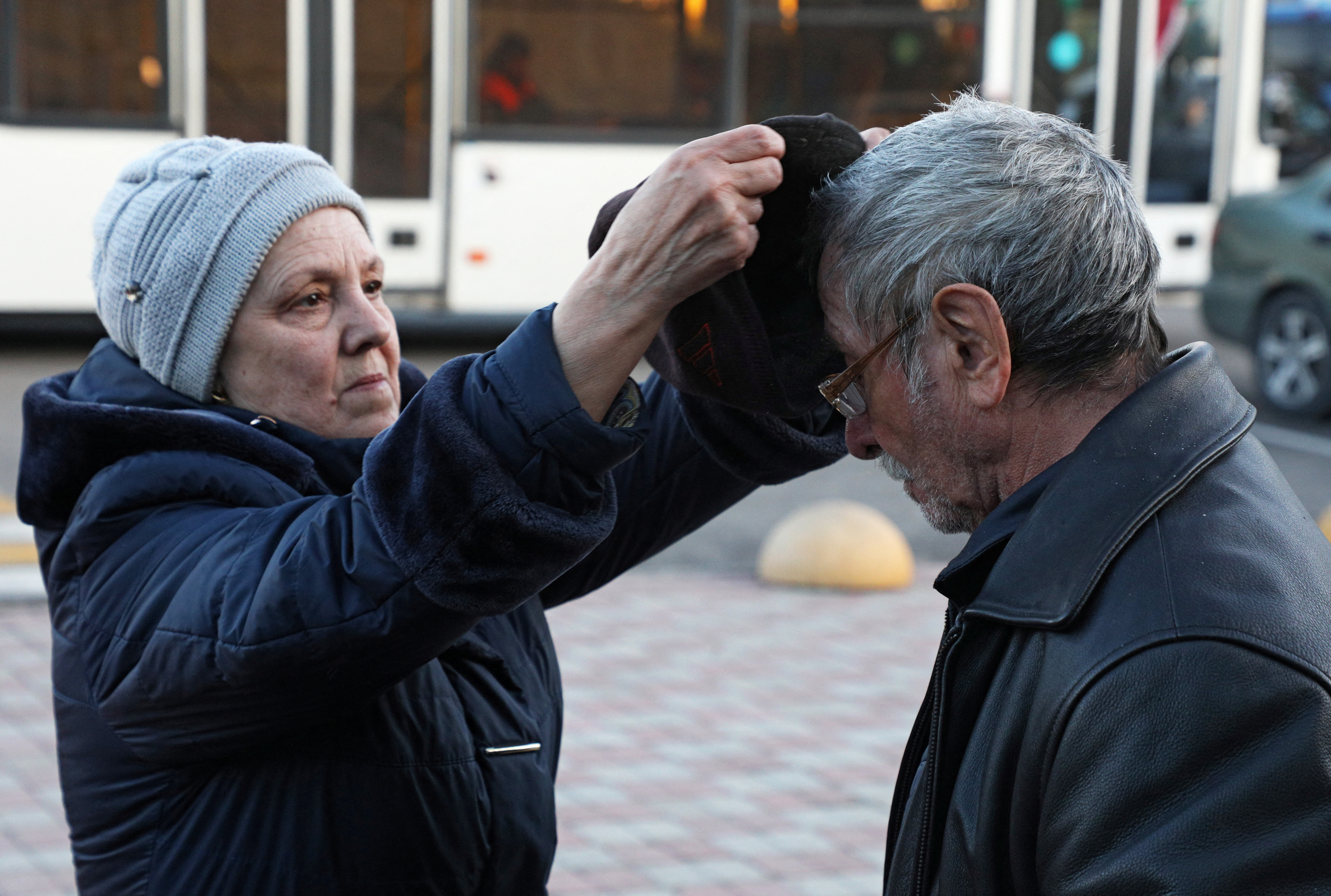 A woman wears a man's hat as citizens evacuated from the Russian-controlled Kherson region of Ukraine arrive at a train station in the city of Zhankoy, Crimea, on October 24, 2022.  REUTERS/Alexey Pavlishak