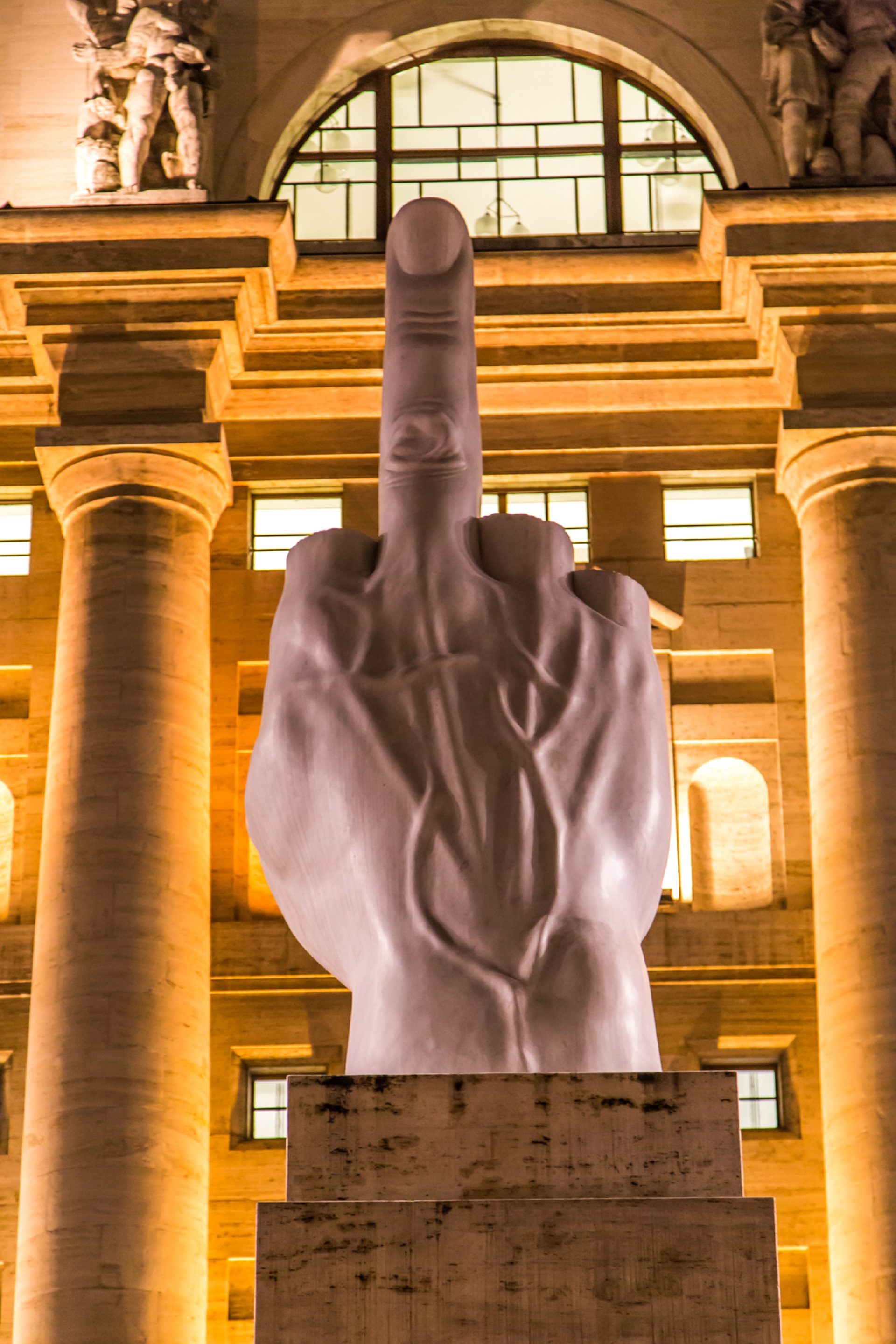 La obra representéiert el saludo romano, pero con los dedos cortados, quedando solo el dedo medio levantado: es un gesto contra un palacio construido pendante el fascismo, pero también contra el poder económico (Foto: Wikipedia / Archiv)