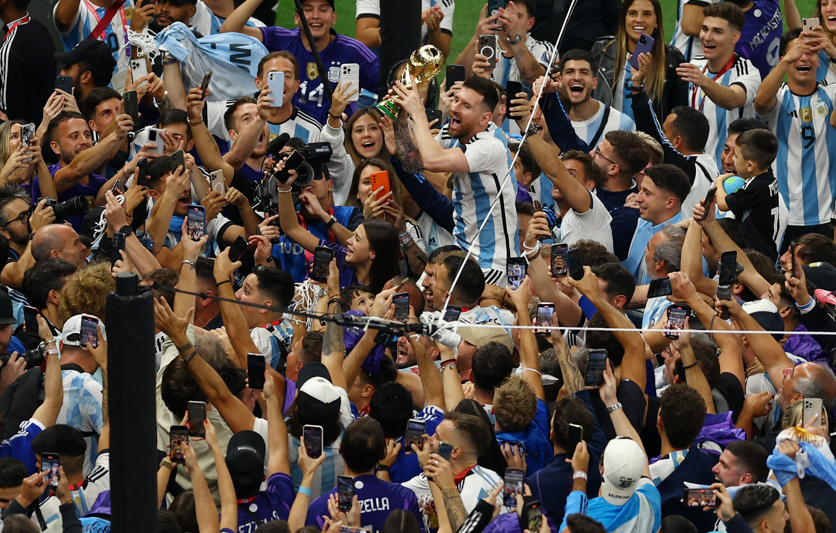Soccer Football - FIFA World Cup Qatar 2022 - Final - Argentina v France - Lusail Stadium, Lusail, Qatar - December 18, 2022 Argentina's Lionel Messi celebrates with the trophy as he is held up by Sergio Aguero after Argentina win the World Cup REUTERS/Molly Darlington
