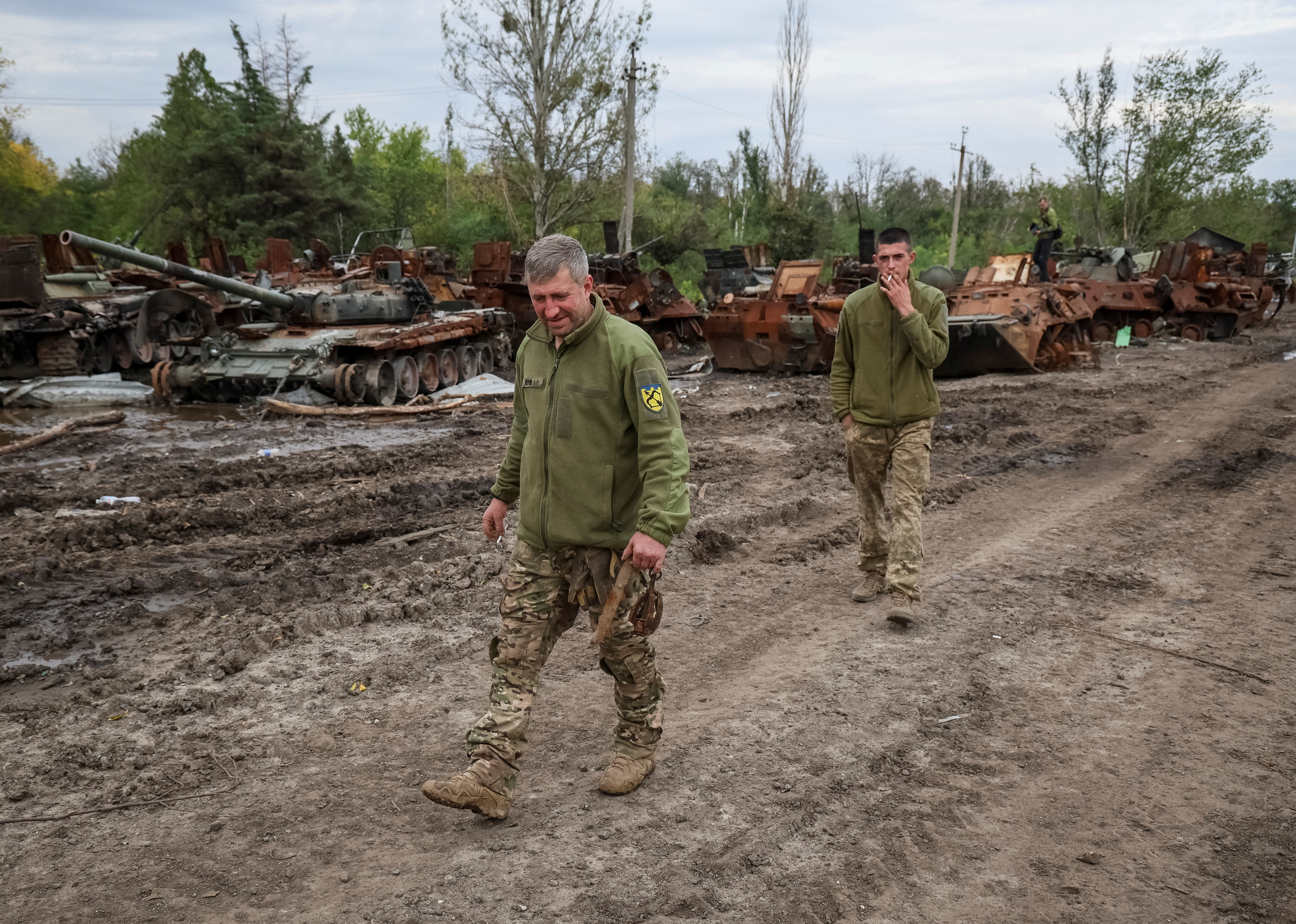 Ukrainske soldater går forbi vraket av en funksjonshemmet russisk stridsvogn i Izium (REUTERS/Gleb Garanich).