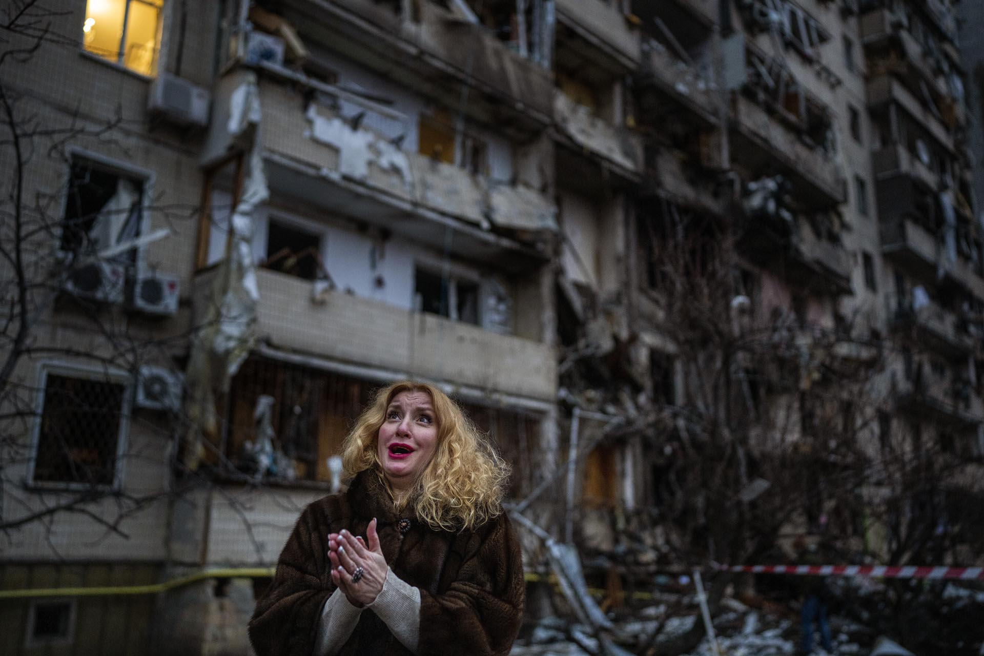 Natali Sevriukova se ve sobrepasada por la emoción, de pie ante su edificio de apartamentos destruido tras un ataque de cohete en Kiev, Ucrania, el viernes 25 de febrero de 2022. 