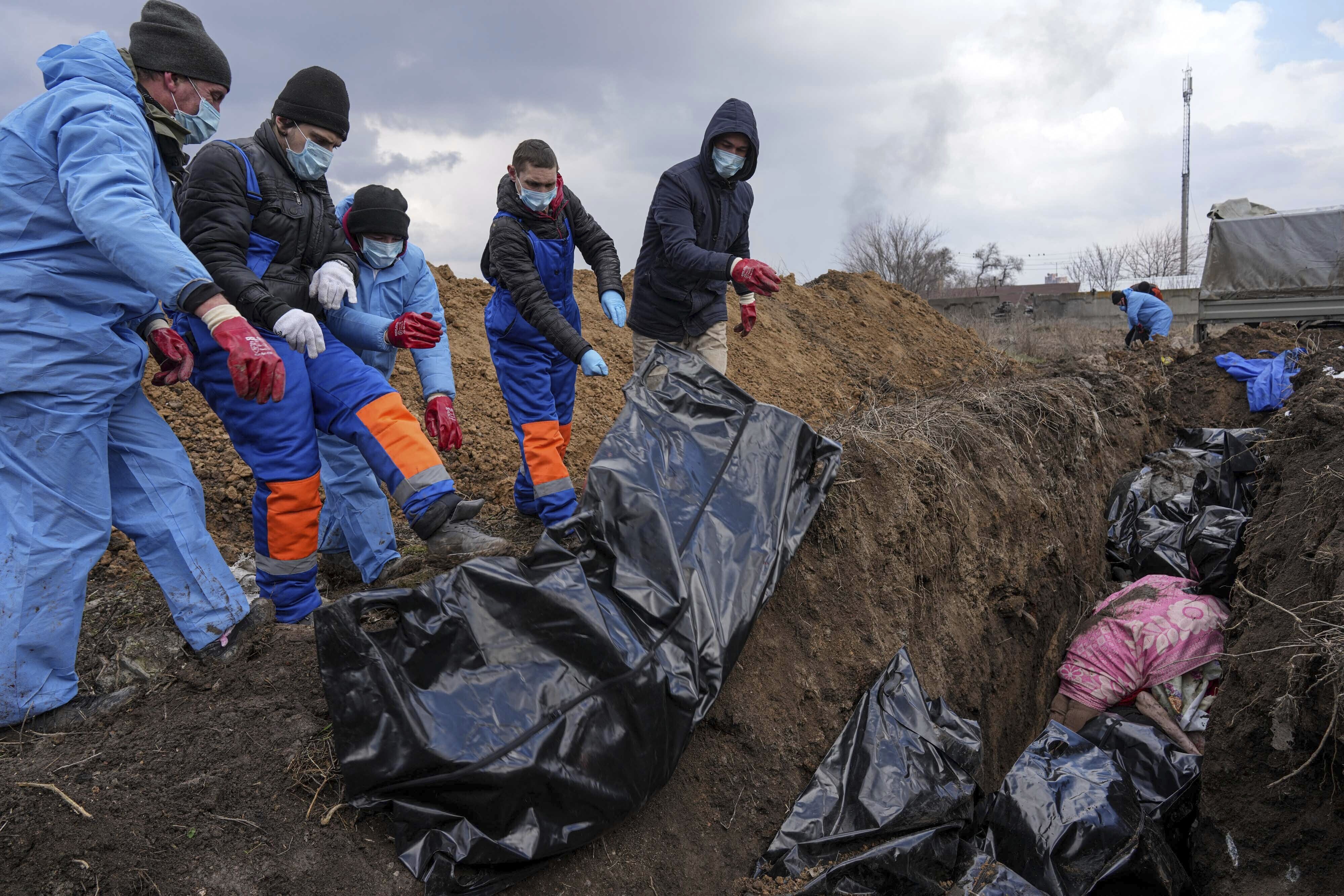 Los cadáveres son colocados en una fosa común en las afueras de Mariupol, Ucrania, el miércoles 9 de marzo de 2022, ya que la gente no puede enterrar a sus muertos debido al fuerte bombardeo de las fuerzas rusas. (AP/Evgeniy Maloletka)