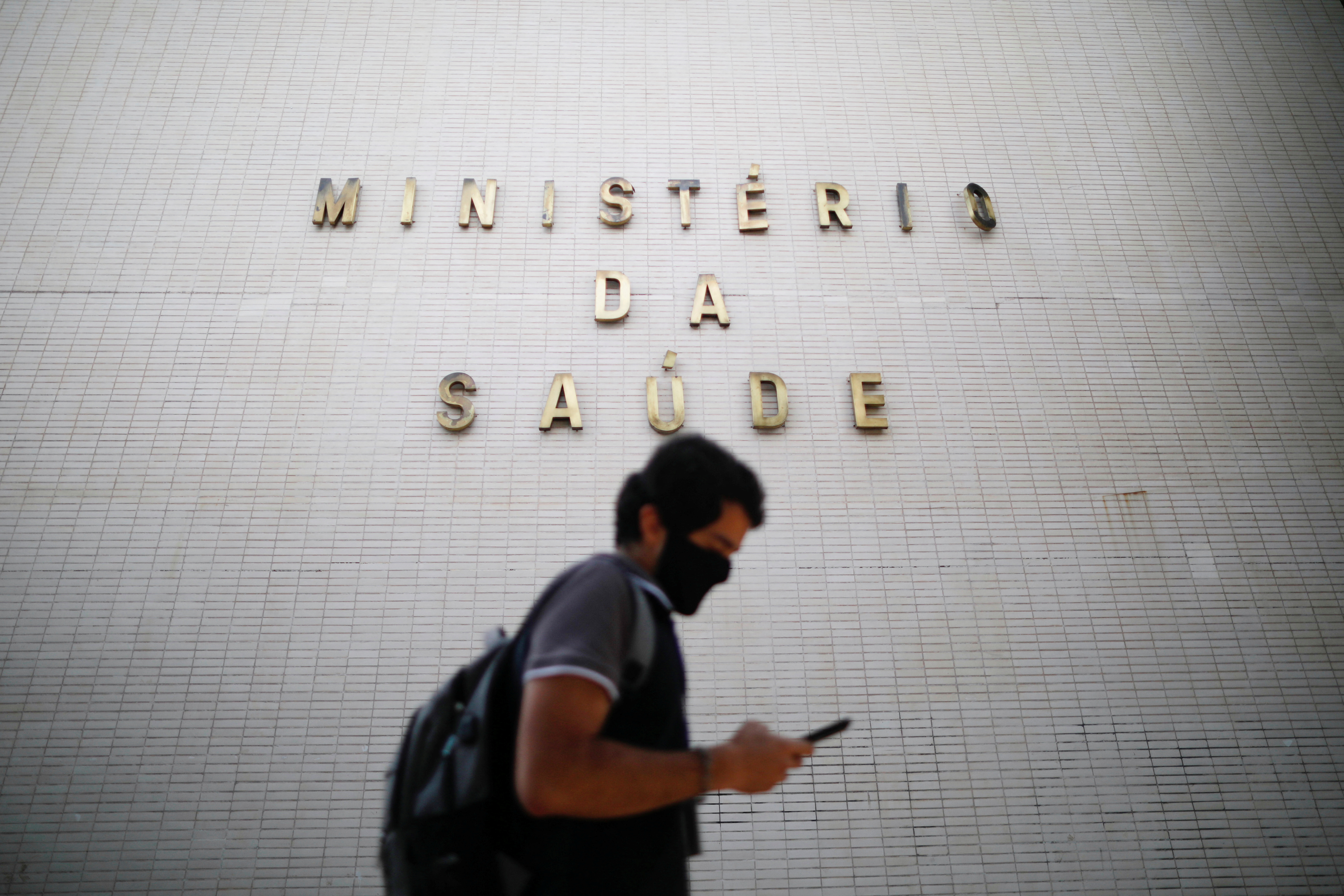 A man uses his cell phone as he walks in front of the headquarters of the Ministry of Health in Brasilia, Brazil, December 10, 2021. REUTERS/Adriano Machado