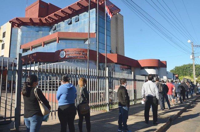 Así esperan, en fila, para entrar a hacer los trámites.