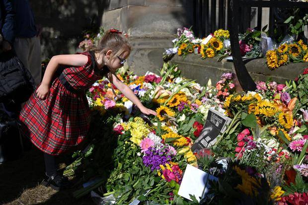 Una niña deja flores afuera del palacio de Edimburgo. Foto: AFP