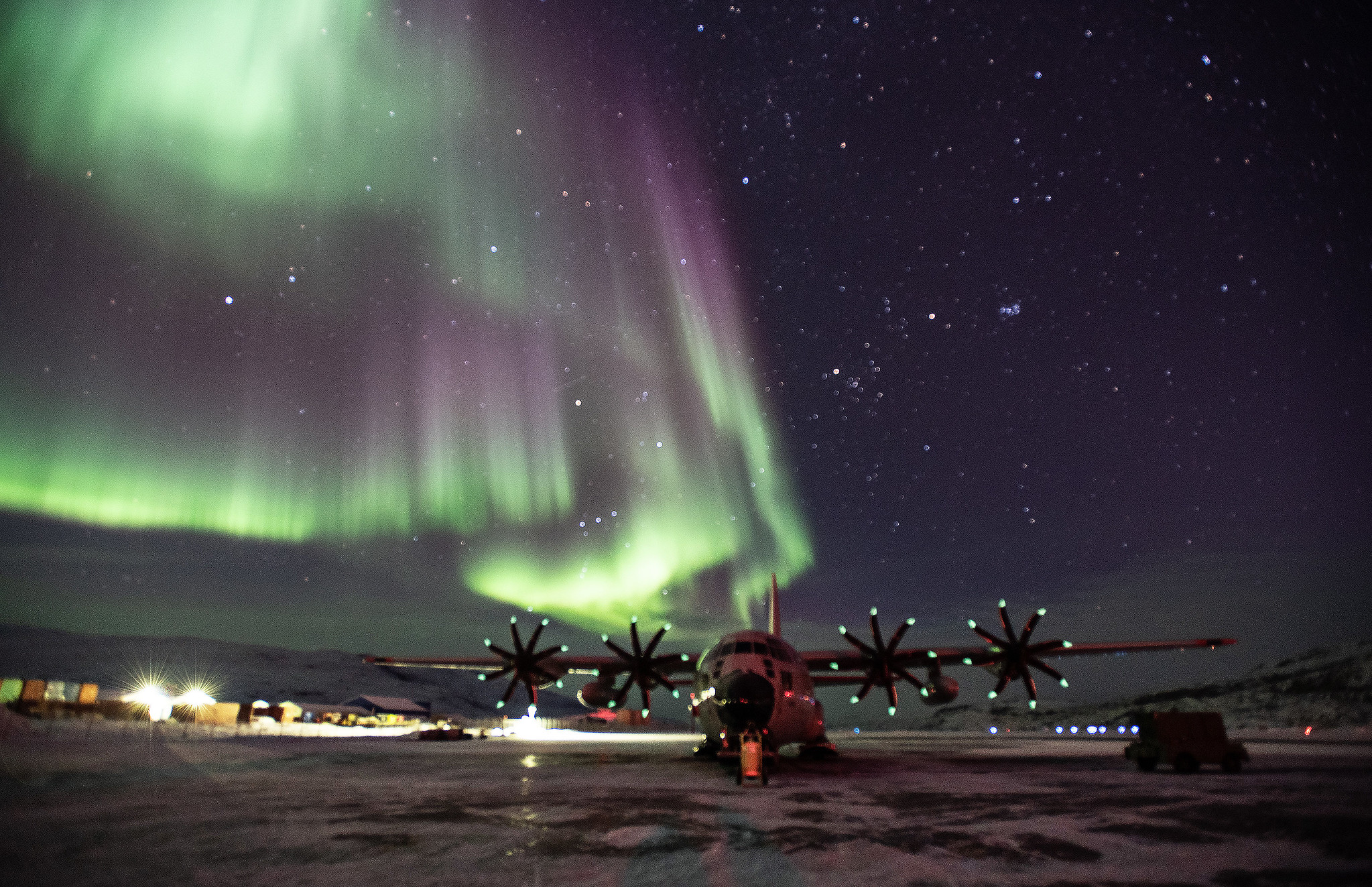 An LC-130 Skibird from the 109th Airlift Wing sits on the ramp at Kangerlussuaq Airport, Greenland, with the Northern Lights dazzling in the sky above. (Lt. Col. Kevin Jones/National Guard)